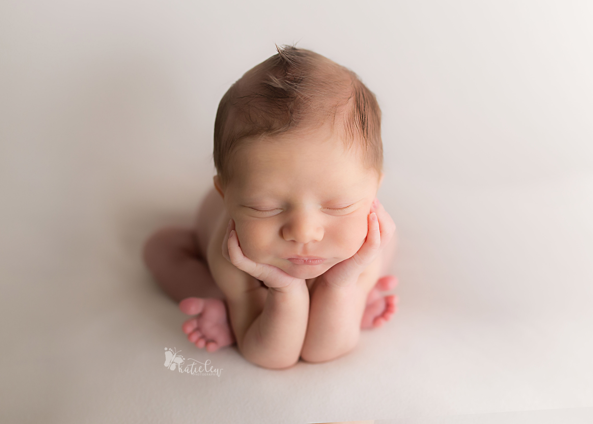 Newborn baby boy in head in hands pose with a mohawk
