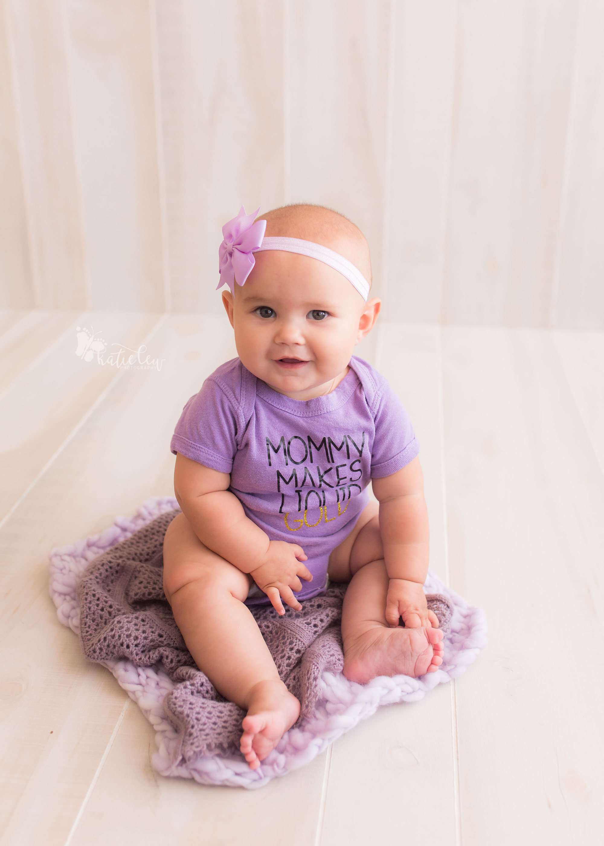 Little baby girl wearing purple "mom makes liquid gold" onesie