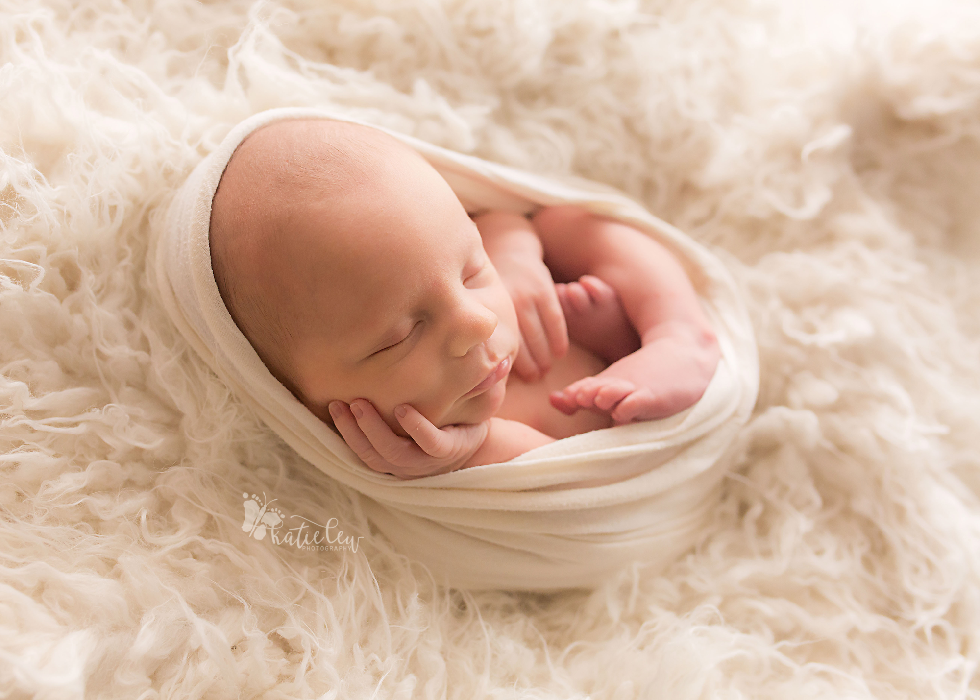 a newborn baby wrapped in a cream wrap and nestled in fur
