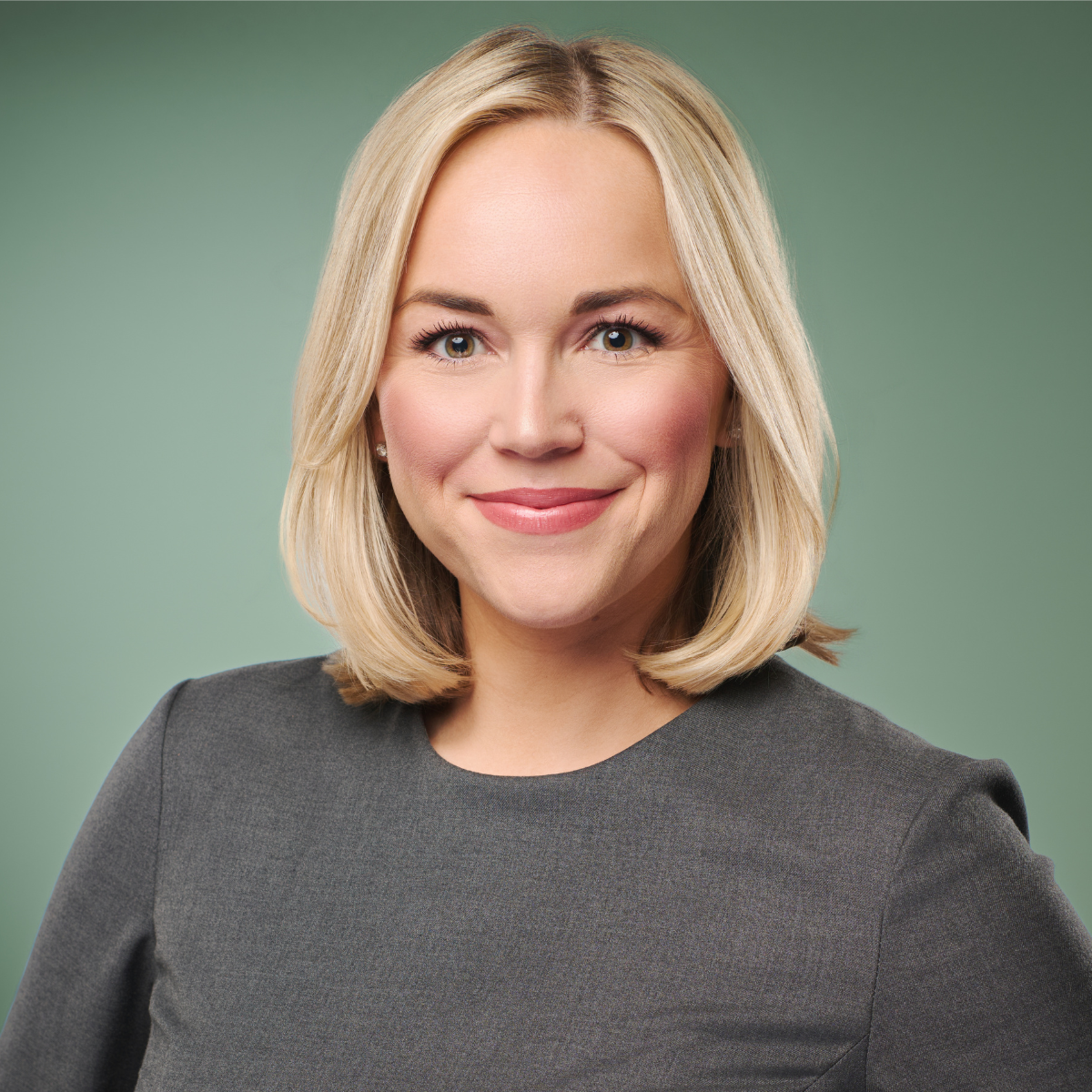 Headshot of woman with blonde hair wearing a grey outfit against a green background from Nashville Headshot Photography Company