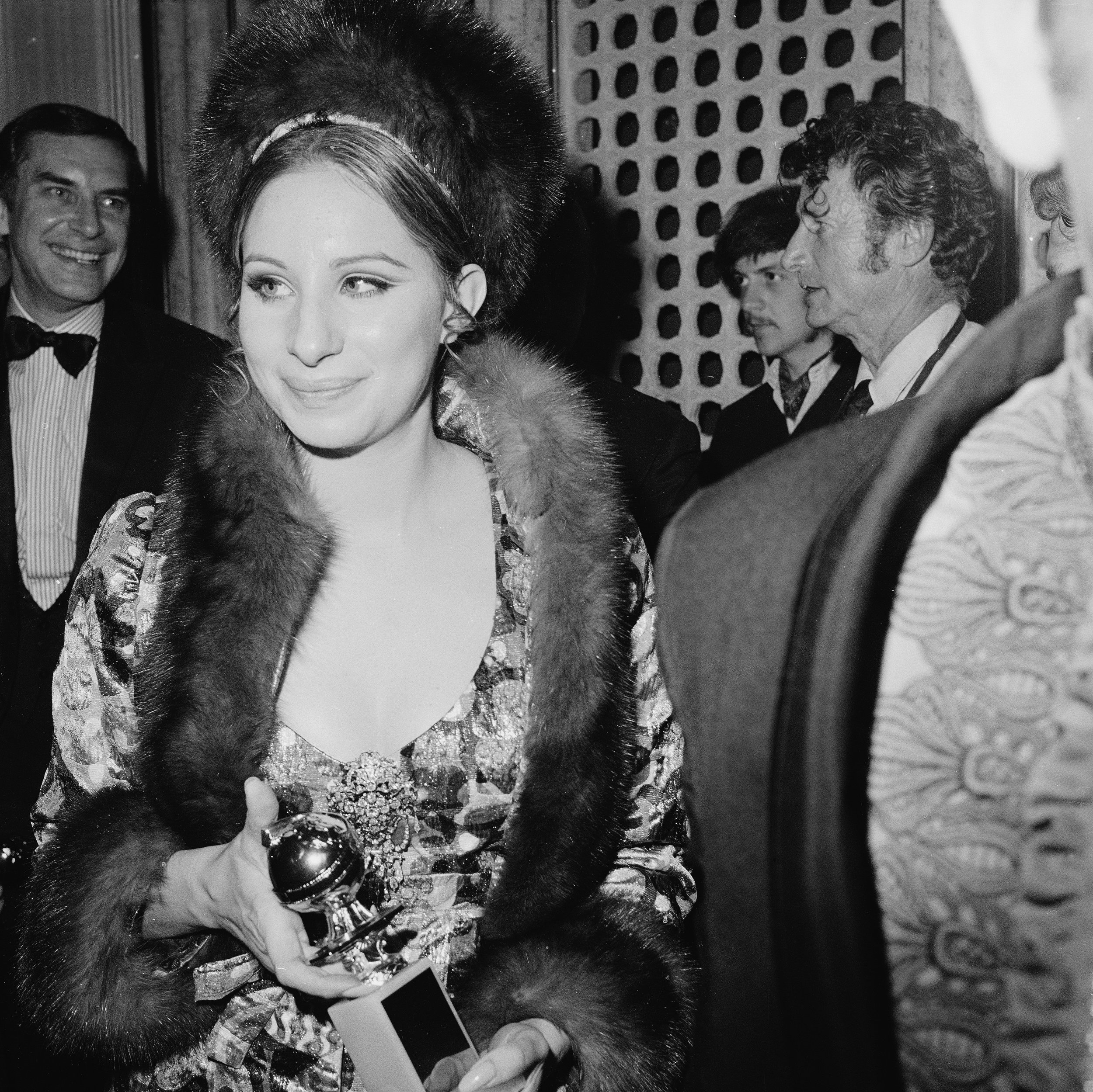 Barbra Streisand—all shimmering brocade and fur—carrying her award for “Best Performance by an Actress in a Motion Picture – Comedy or Musical” during the 26th Annual Golden Globe Awards on February 28, 1969.