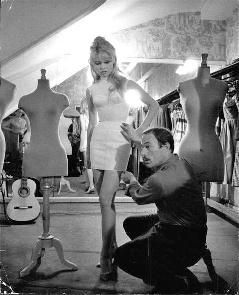 BRIGITTE BARDOT BEING FITTED BY JACQUES ESTEREL, 1958.