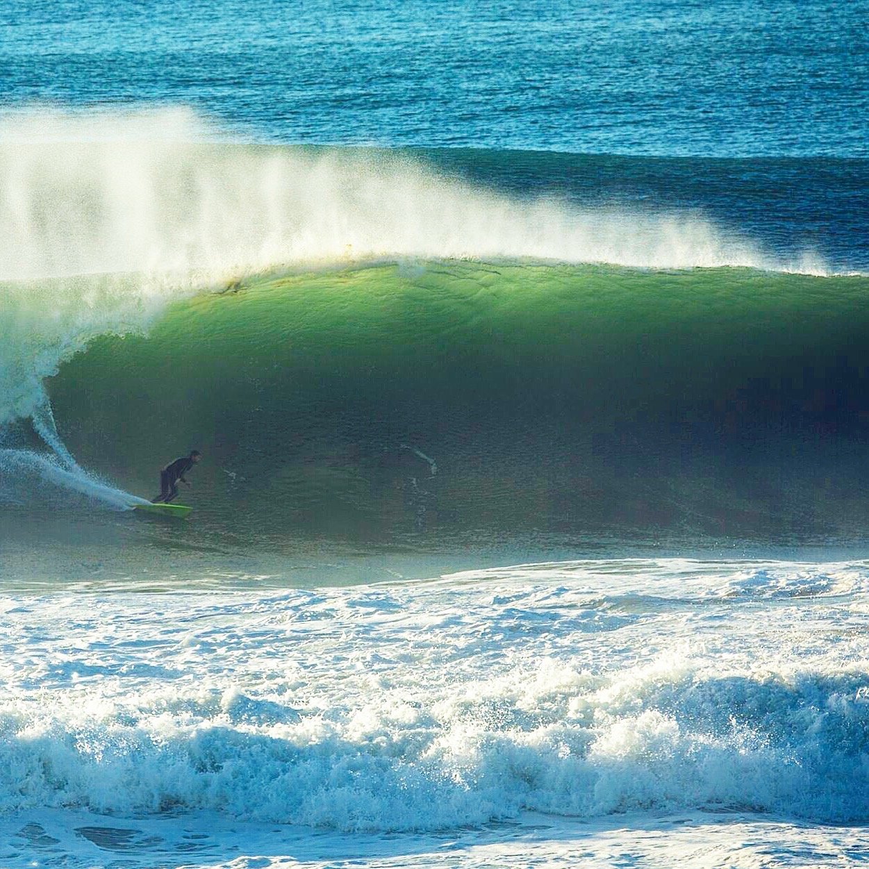 A surfer riding inside the barrel of a large ocean wave.