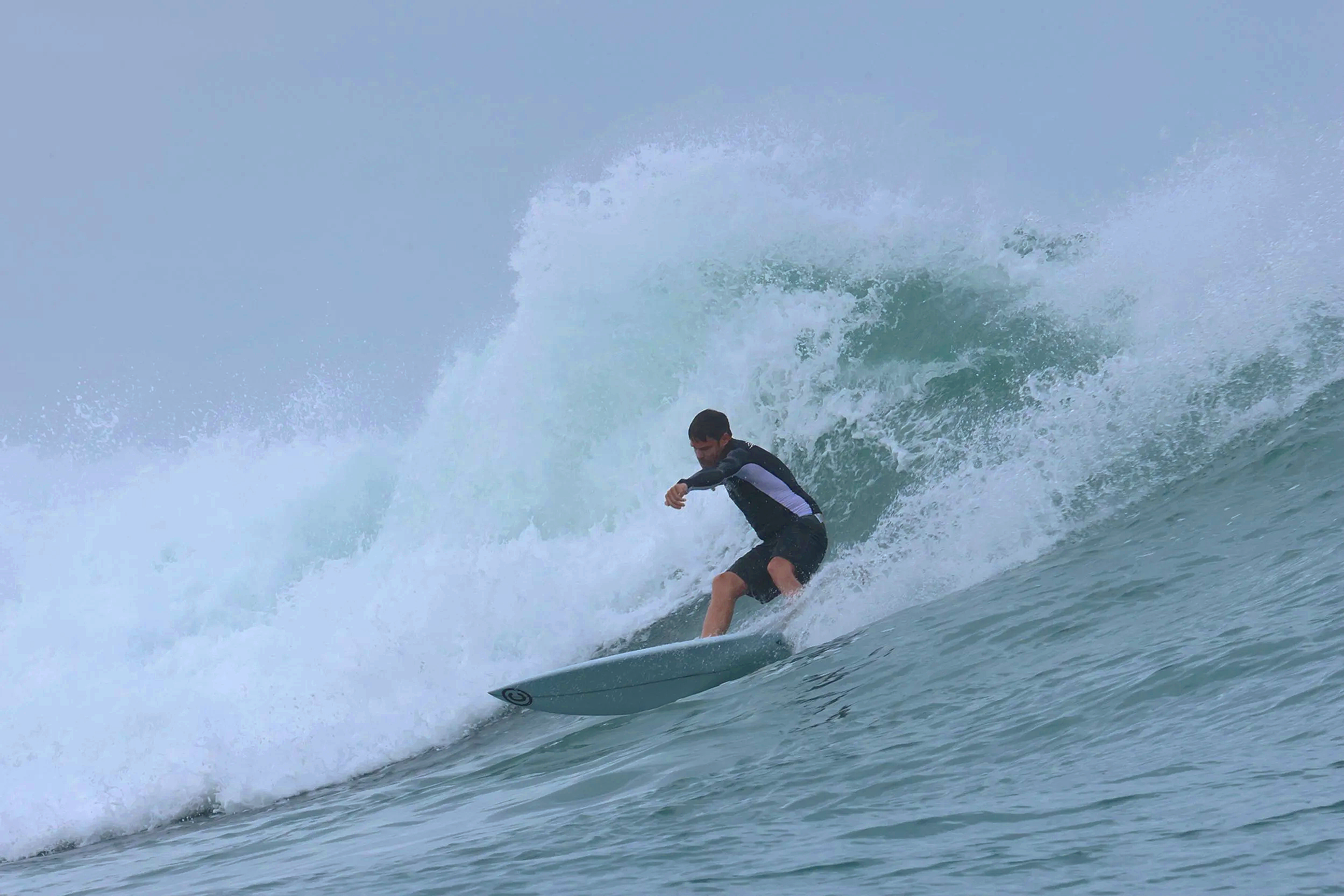 A surfer riding a large wave on the ocean during daytime.
