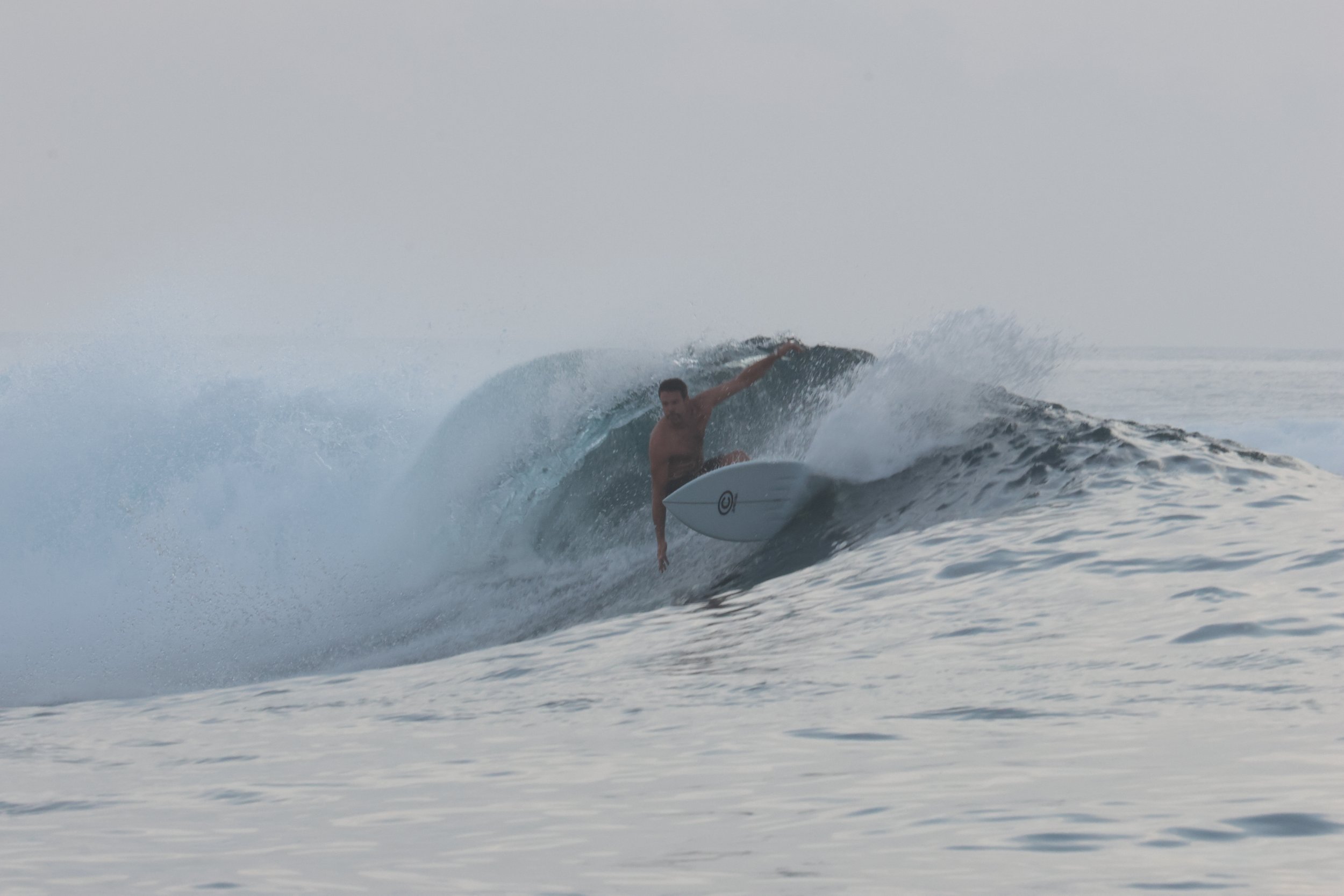 A shirtless man surfing on a wave in the ocean during daytime.