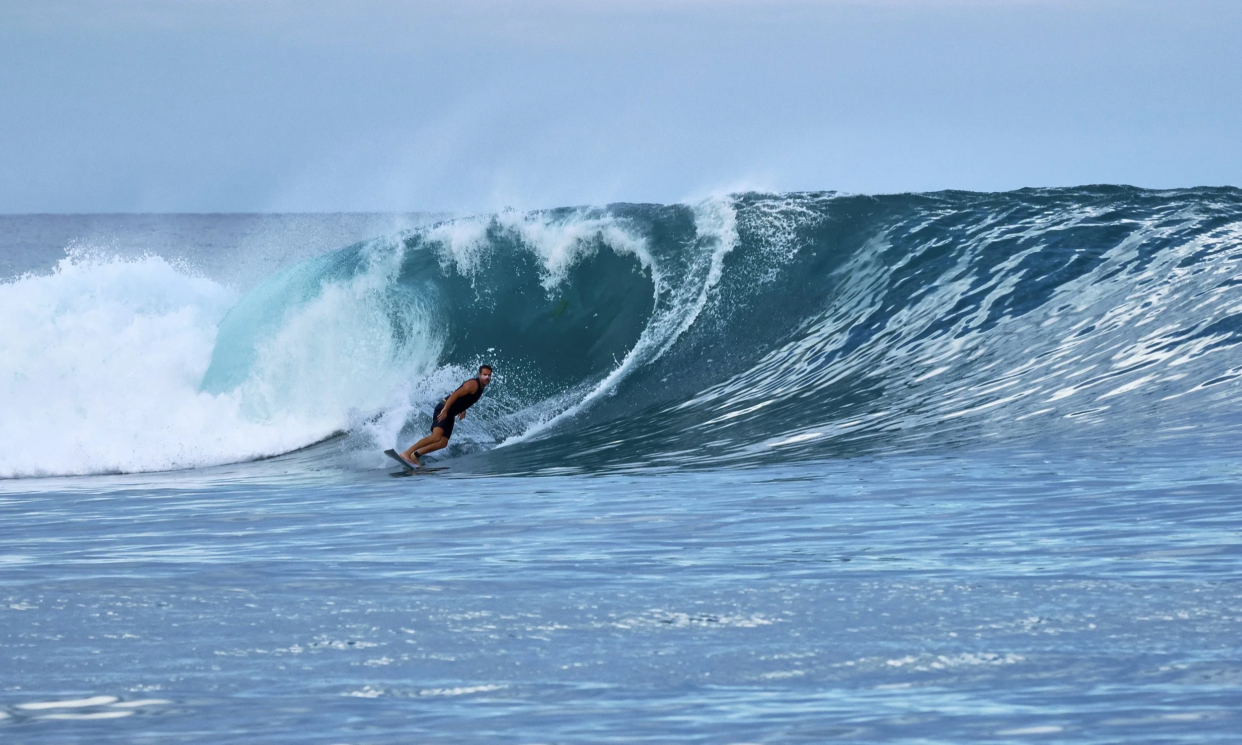 A person surfing on a large wave in the ocean.