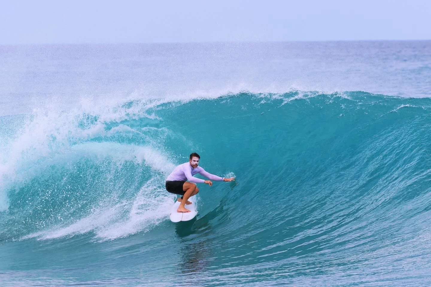 A man surfing on a large breaking wave in the ocean.