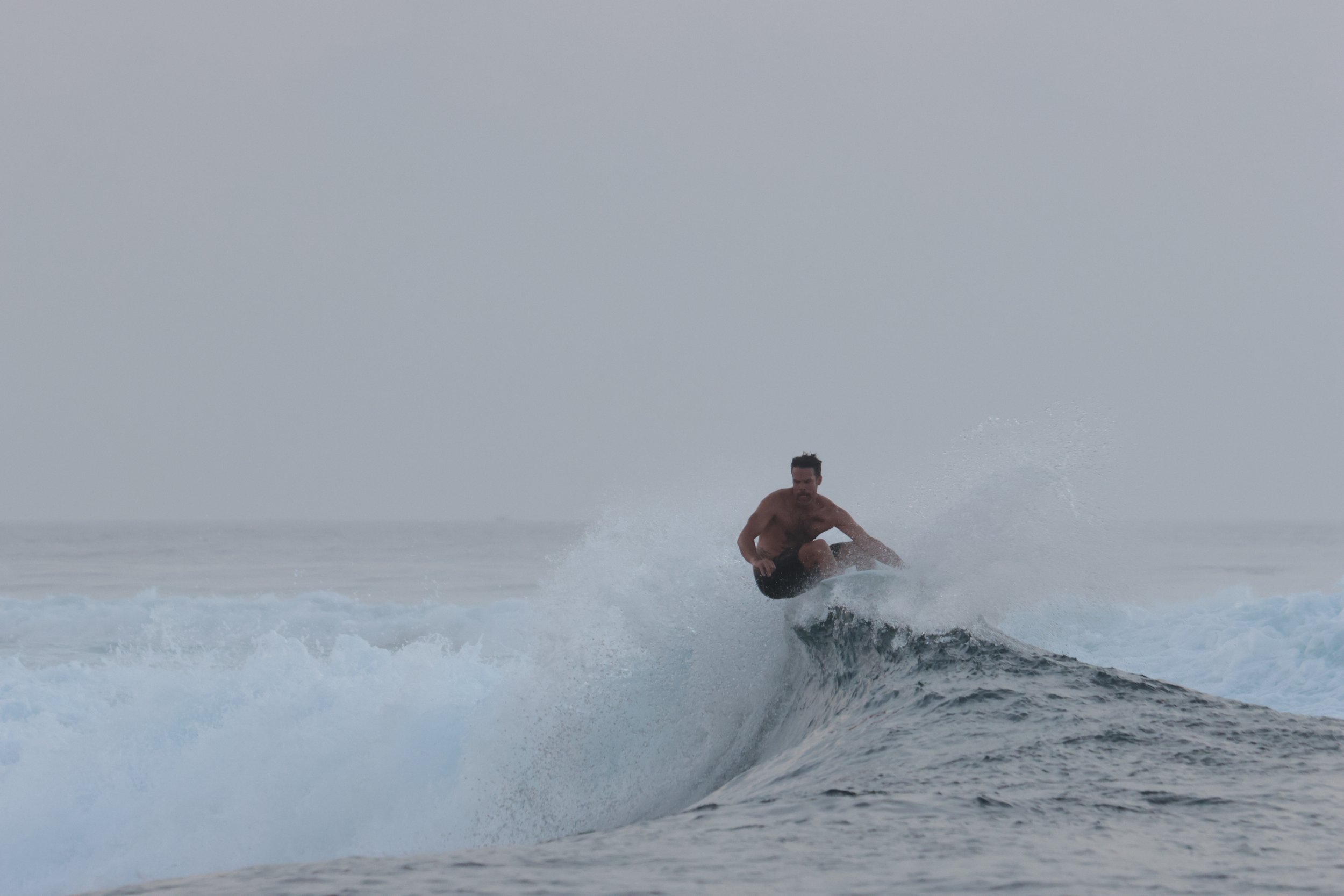 A man surfing on a wave in the ocean.