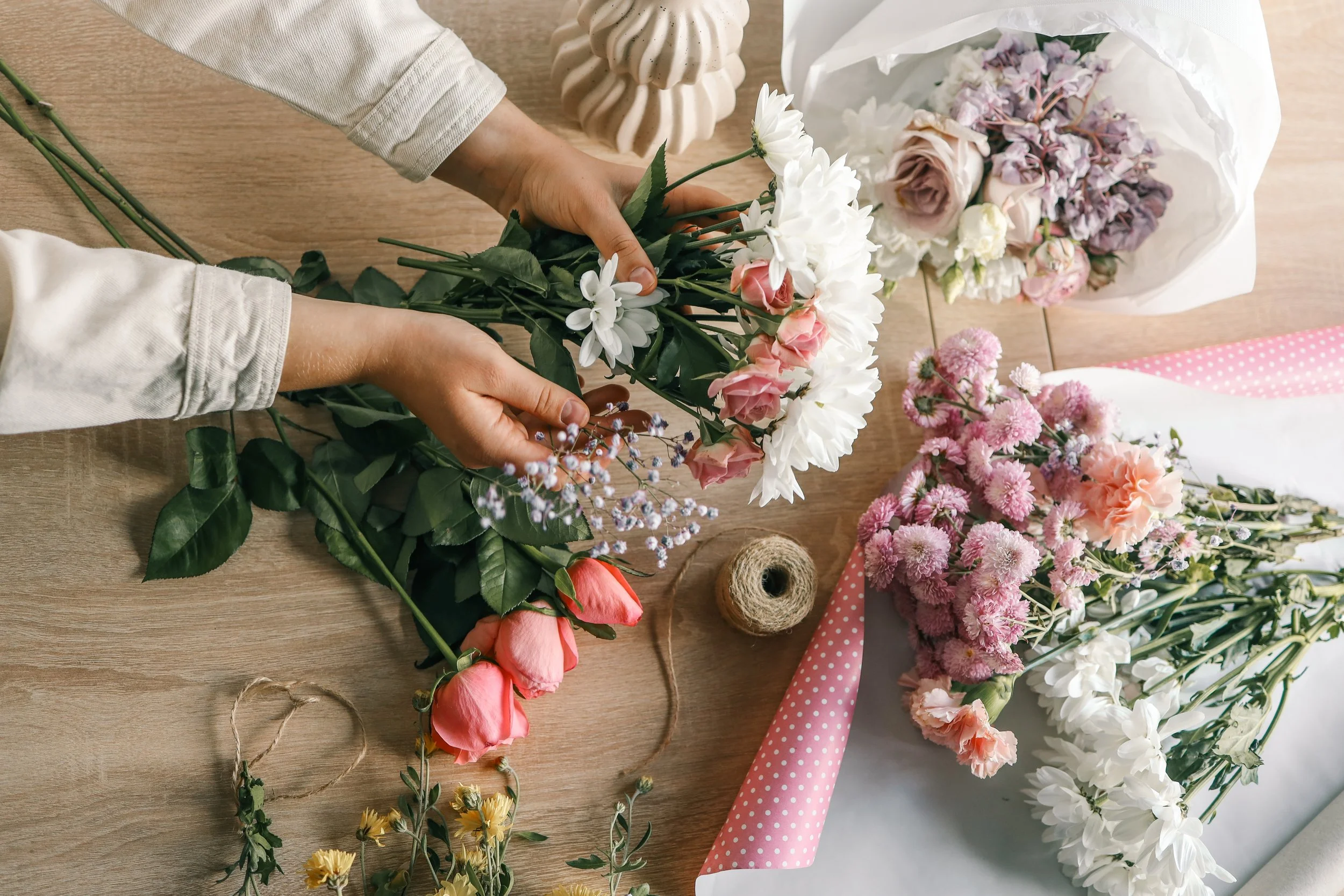 Hands arranging flowers on a table