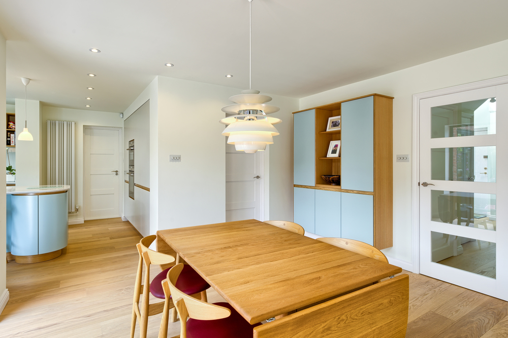 Wooden table and low hanging light of a Scandinavian house extension by Harvey Norman Architects Bishop's Stortford