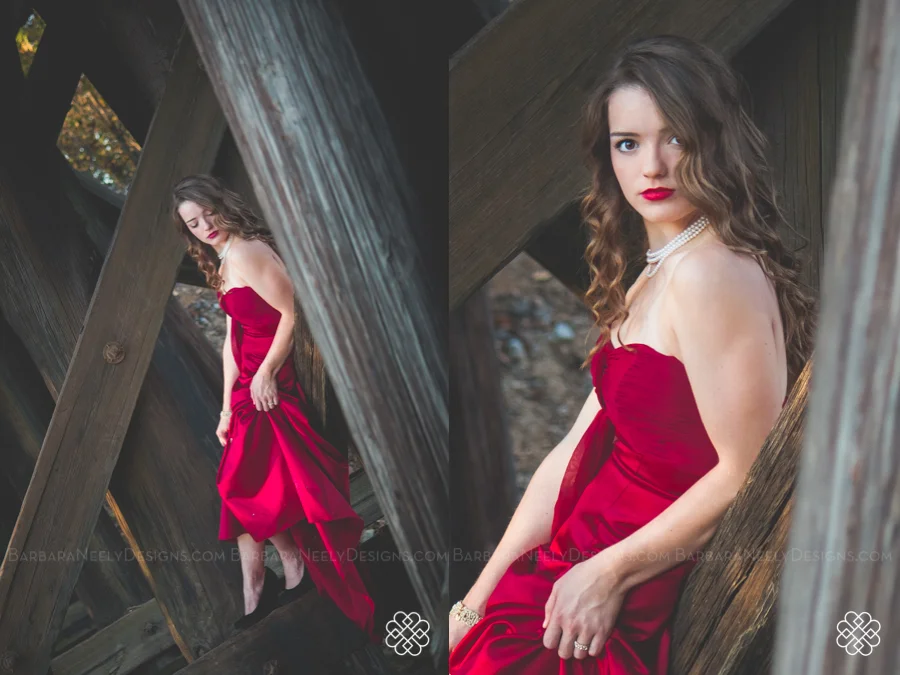 Very dramatic senior girl in red prom dress on railroad truss