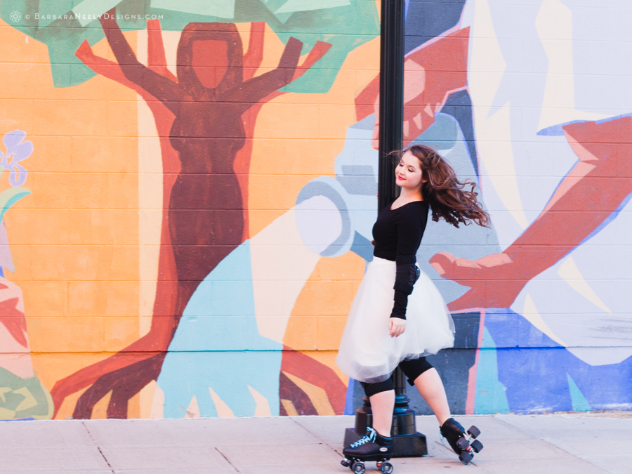 Vibrant senior girl in roller skates in front of mural