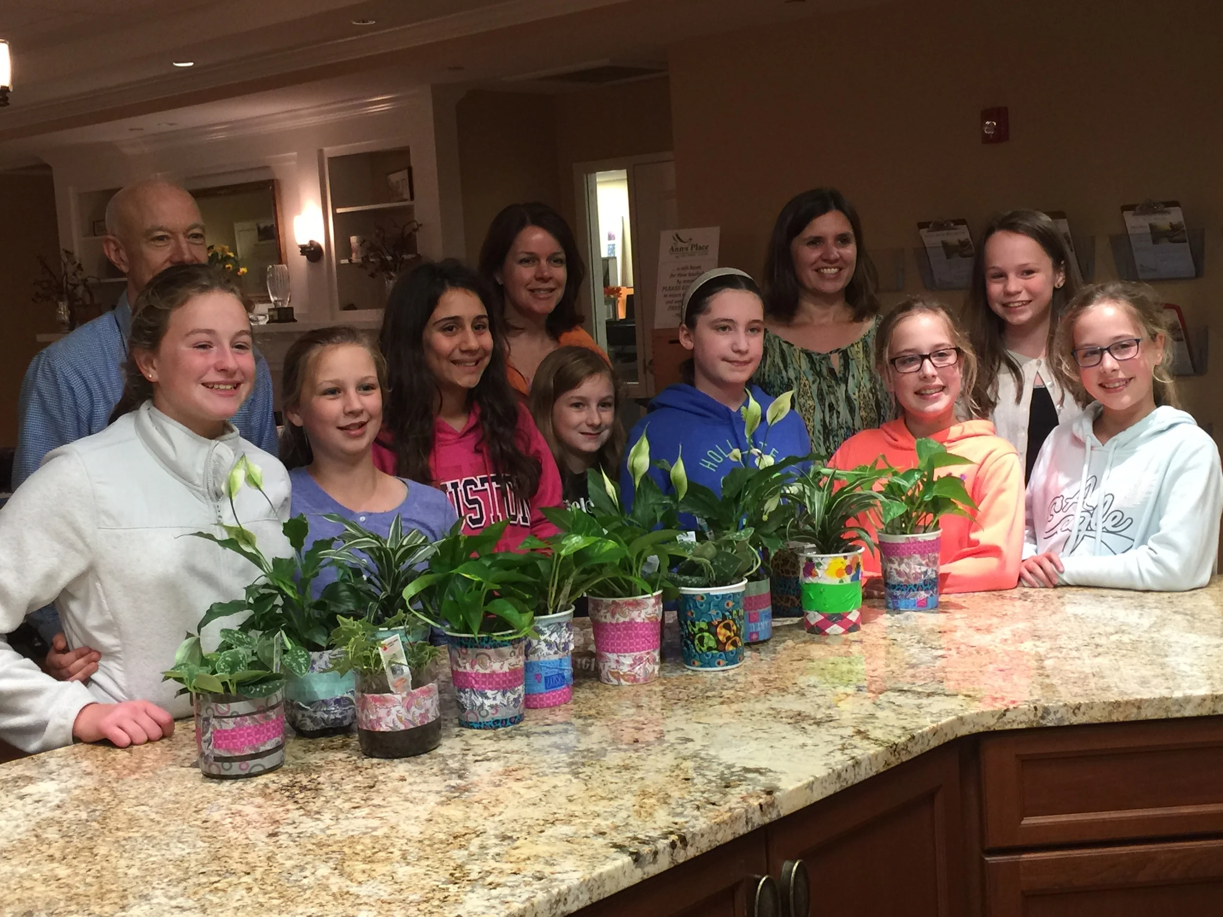 Members of Girl Scout Troop 50286 present purifying plants to Kevin Berrill, MSW, LCSW and Laura Donnelly, MSW, LCSW - Ann's Place