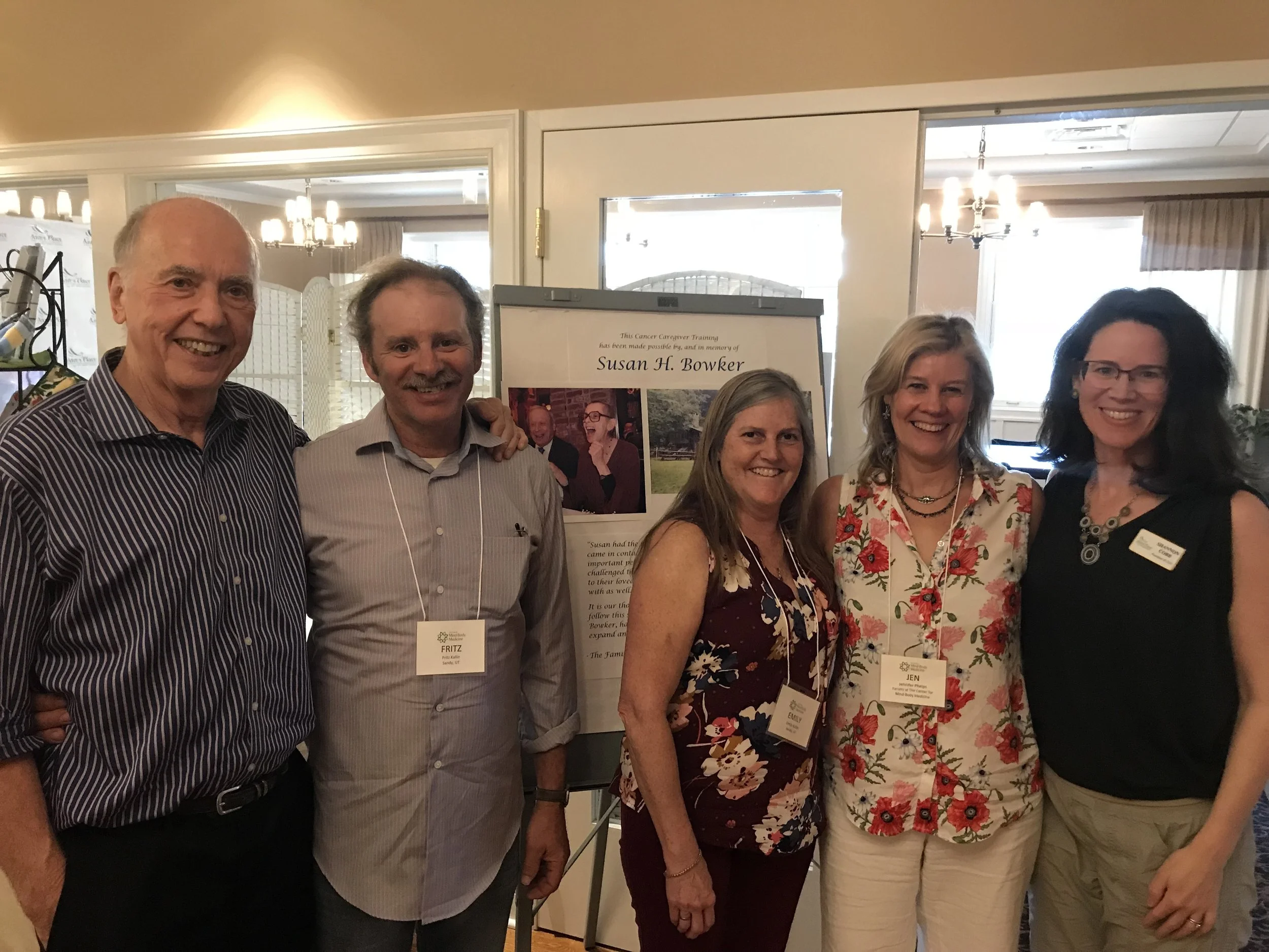 James S. Gordon M.D., Founder and Executive Director of The Center for Mind-Body Medicine; Fritz Kallin and Emily Kallin (son and daughter-in-law of Susan H. Bowker); Jennifer Phelps, Owner, Phelps MD Integrative Medicine, and Shannon Cobb, President and CEO of Ann’s Place, stand in front of a photo of Susan Bowker. Over 105 professional cancer caregivers received a full scholarship to come to Ann’s Place for a 4-day training on mind-body wellness.