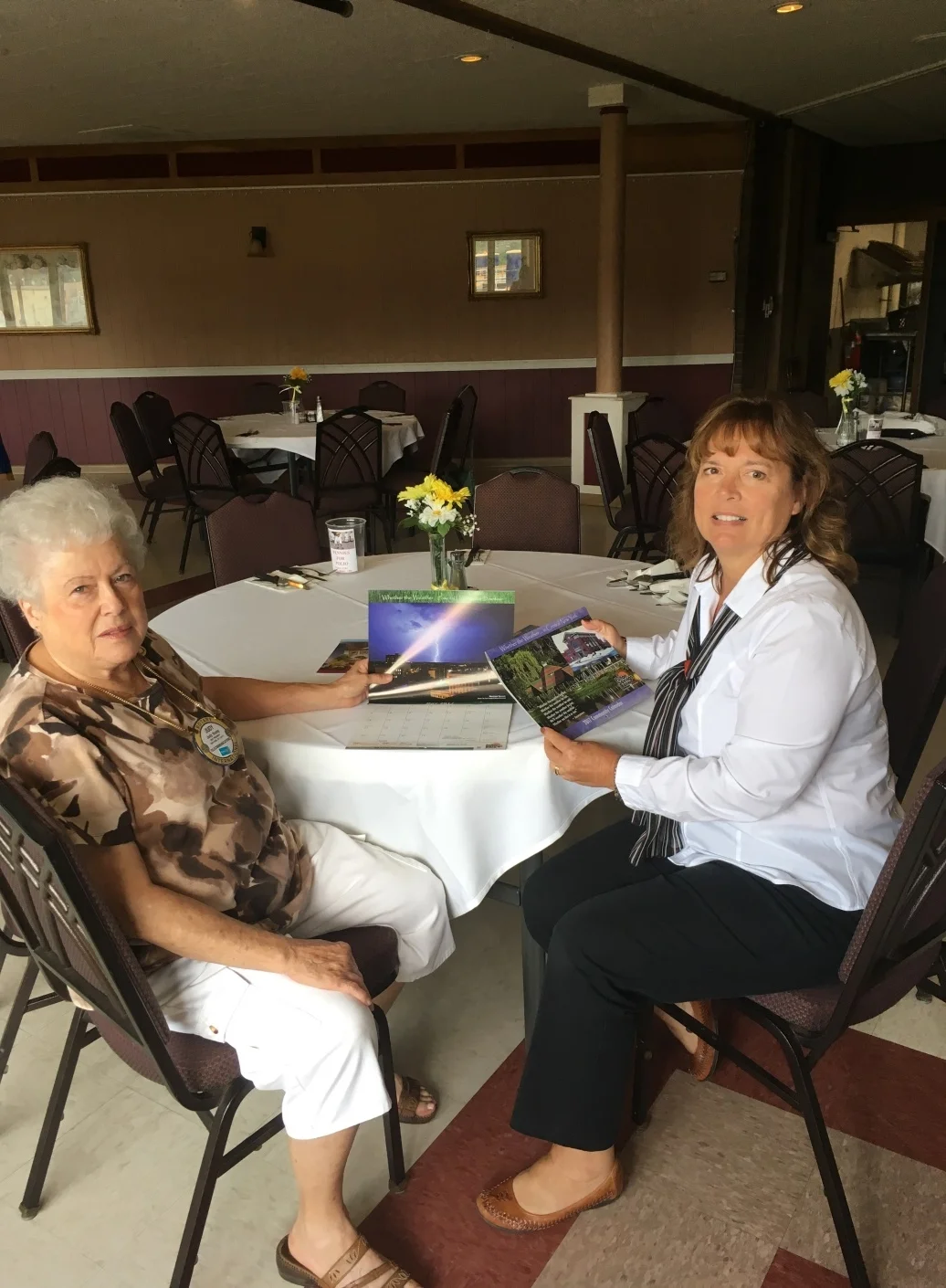 Nancy Kush Ellis, right, shows Judy Young some of the Fulton Savings Bank's calendars. Judy has collected each year's calendar since 1996.