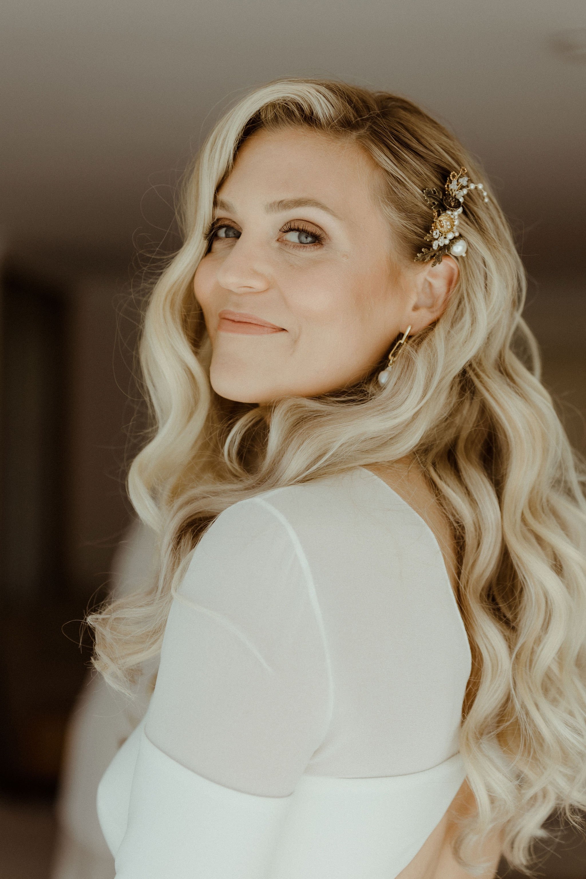 Blonde bride with wavy hair looking to camera the morning of her wedding. Bridal portrait for October East Sussex wedding