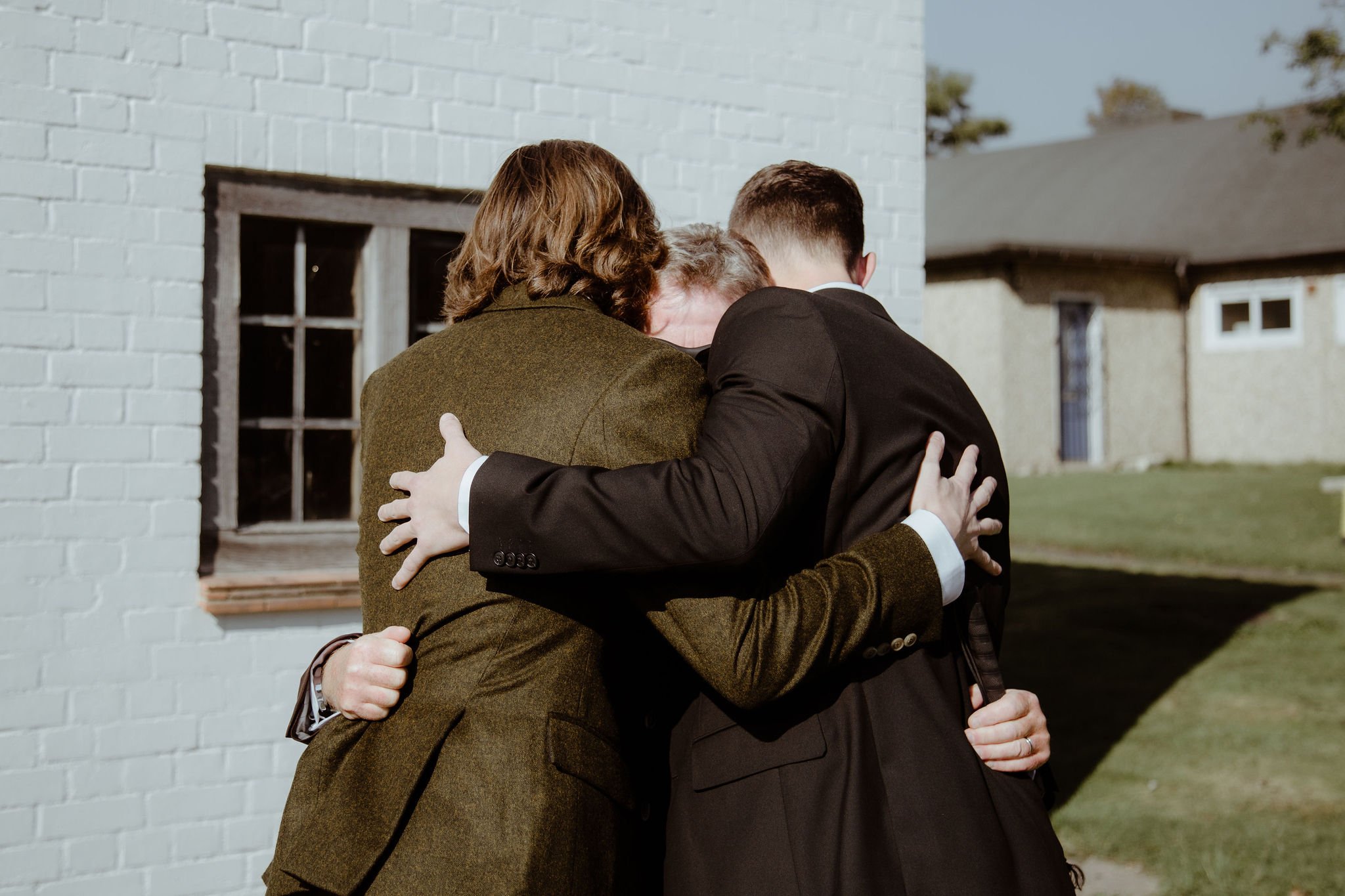 Groom, brother and father hug the morning of his wedding in candid photograph outside Sussex church 