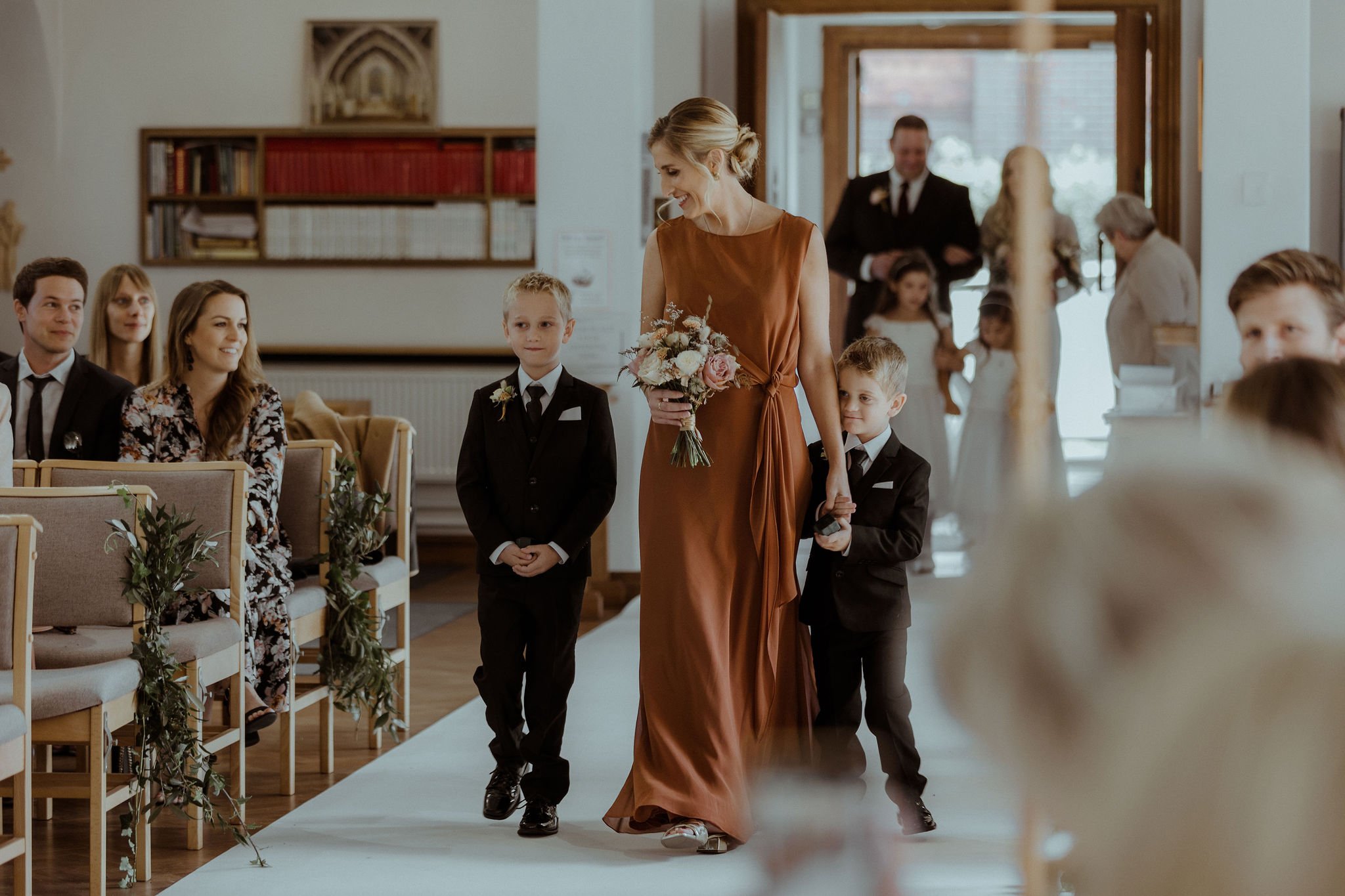 Bridesmaid and page boys walking up aisle together for autumnal church wedding
