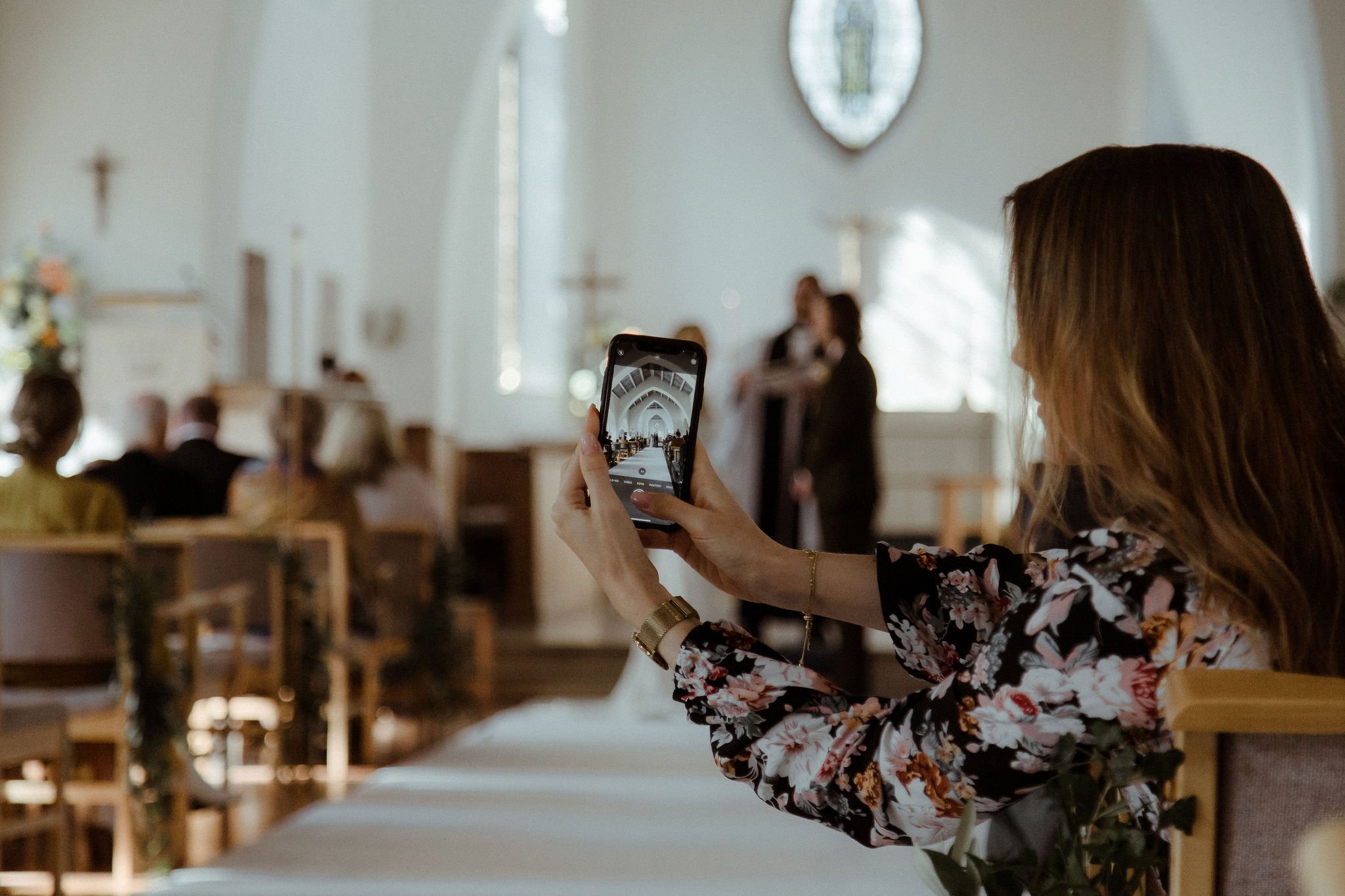 Guest taking photo on their iPhone during wedding ceremony