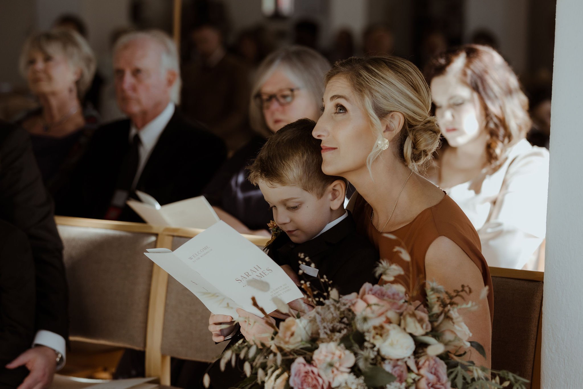 Pageboy reading wedding order of service during wedding ceremony in church