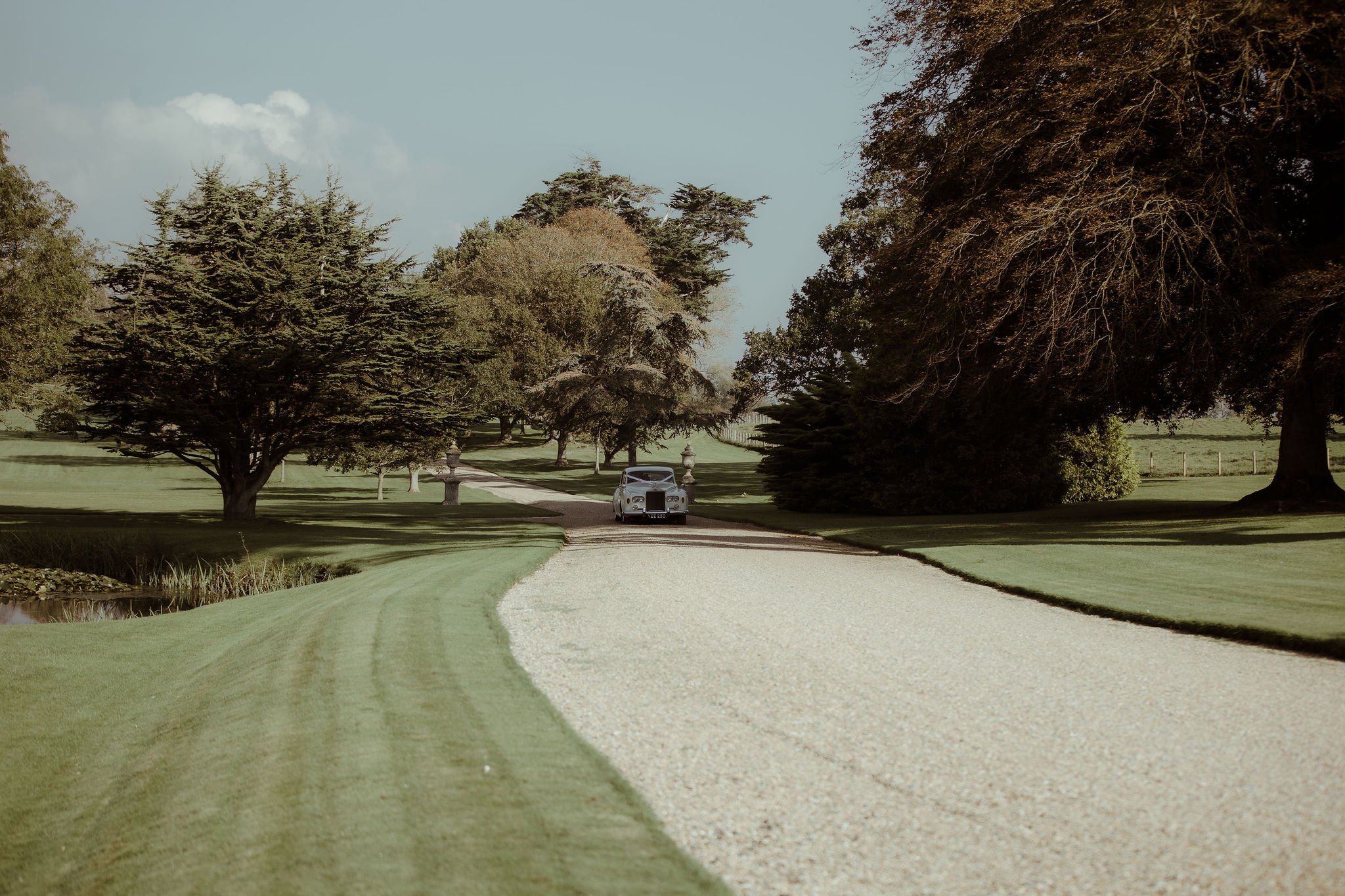 Cream vintage wedding car arriving at Folkington Manor on sweeping driveway