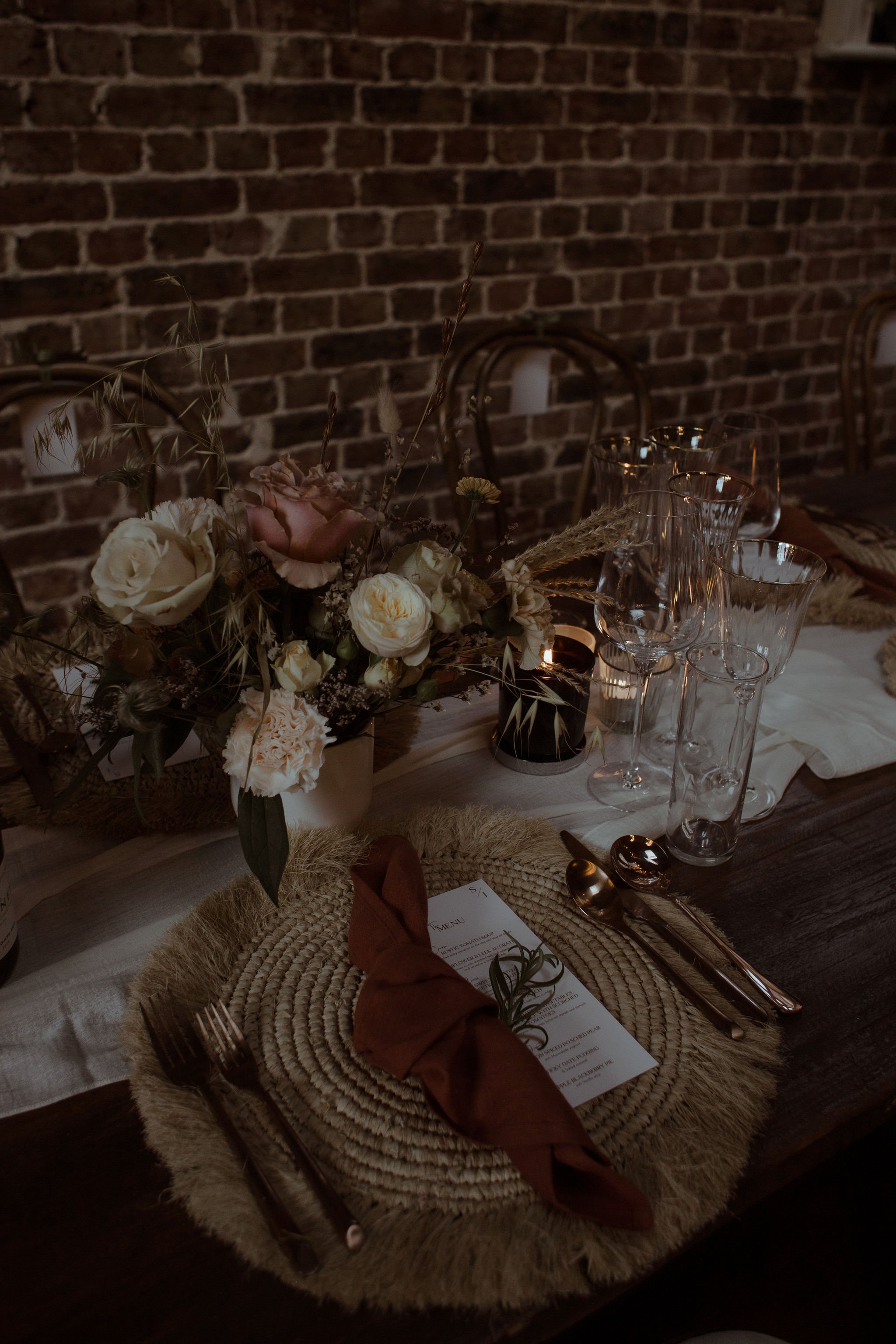 Rustic winter wedding place setting. Gold cutlery, terracotta wedding napkins, dried florals, jute placemats for October wedding at Folkington Manor. Candlelight wedding dinner in Scotland wedding