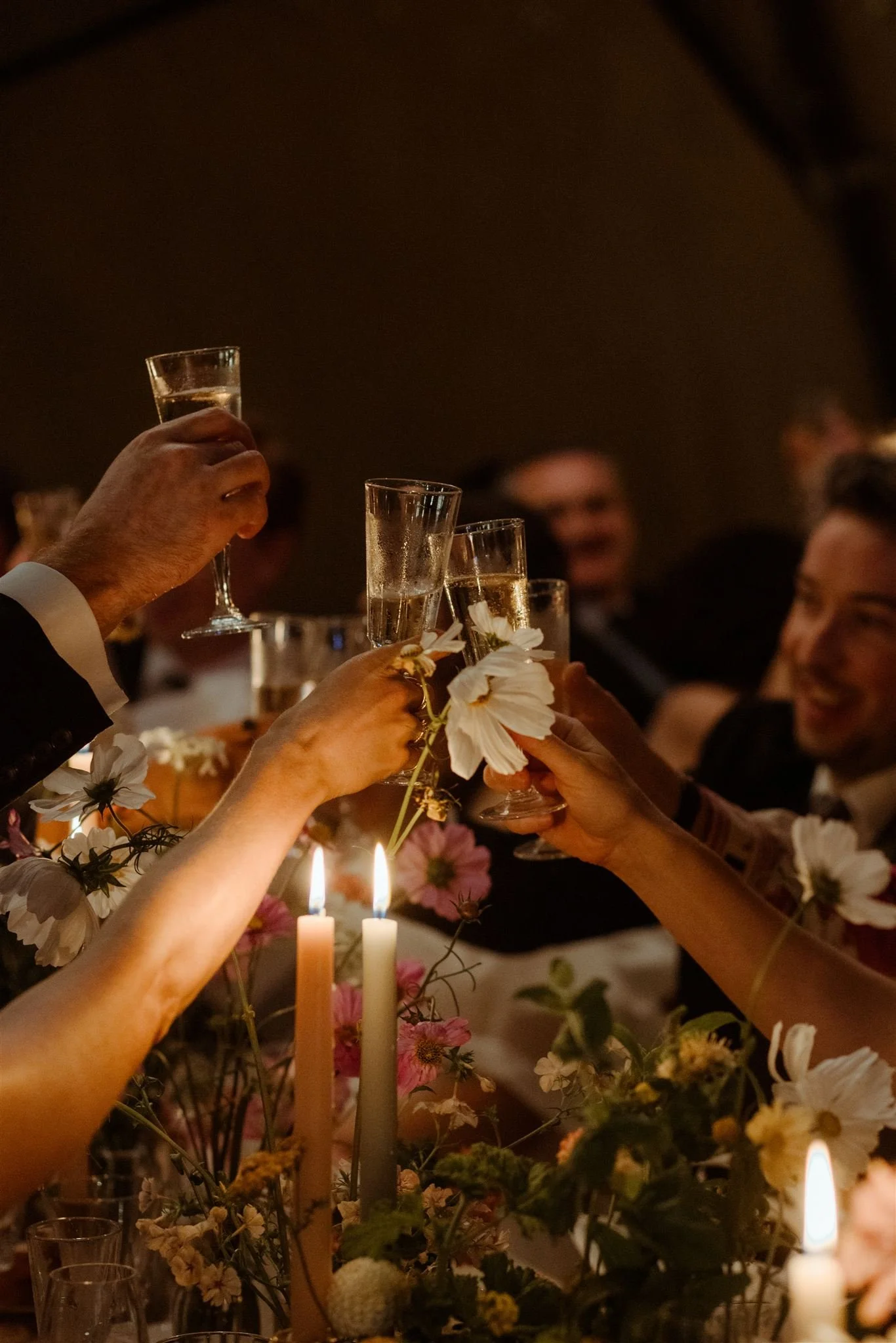 Close up of glasses toasting during candlelit wedding reception