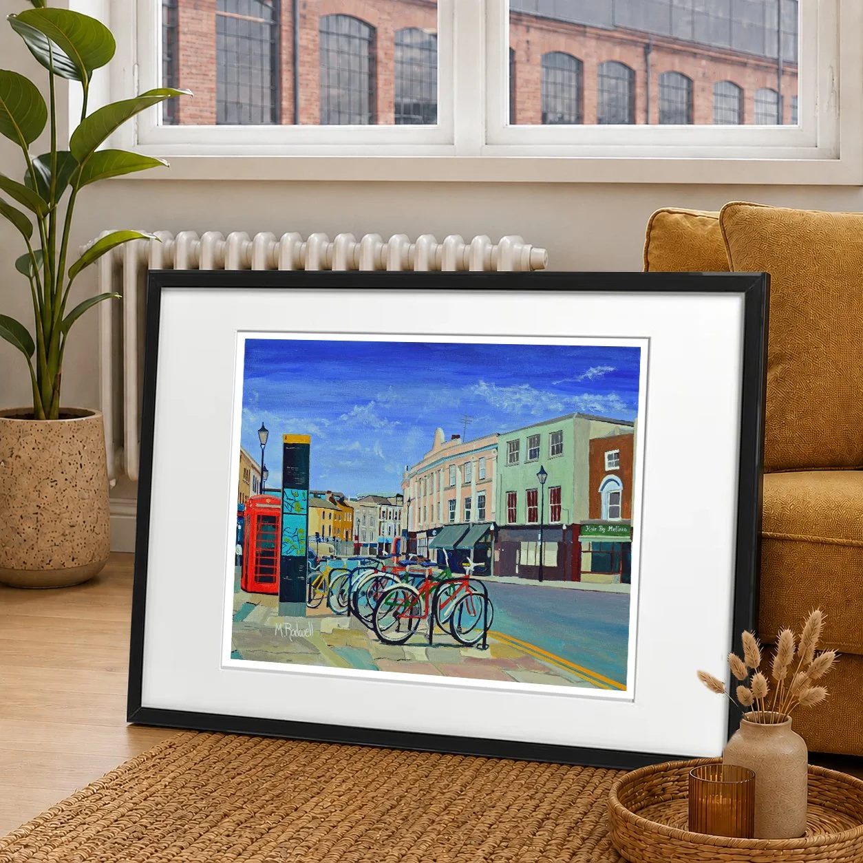 Colour illustration of Greenwich featuring the high street looking onto the market.  Cycles and phone box representing typical British high street.