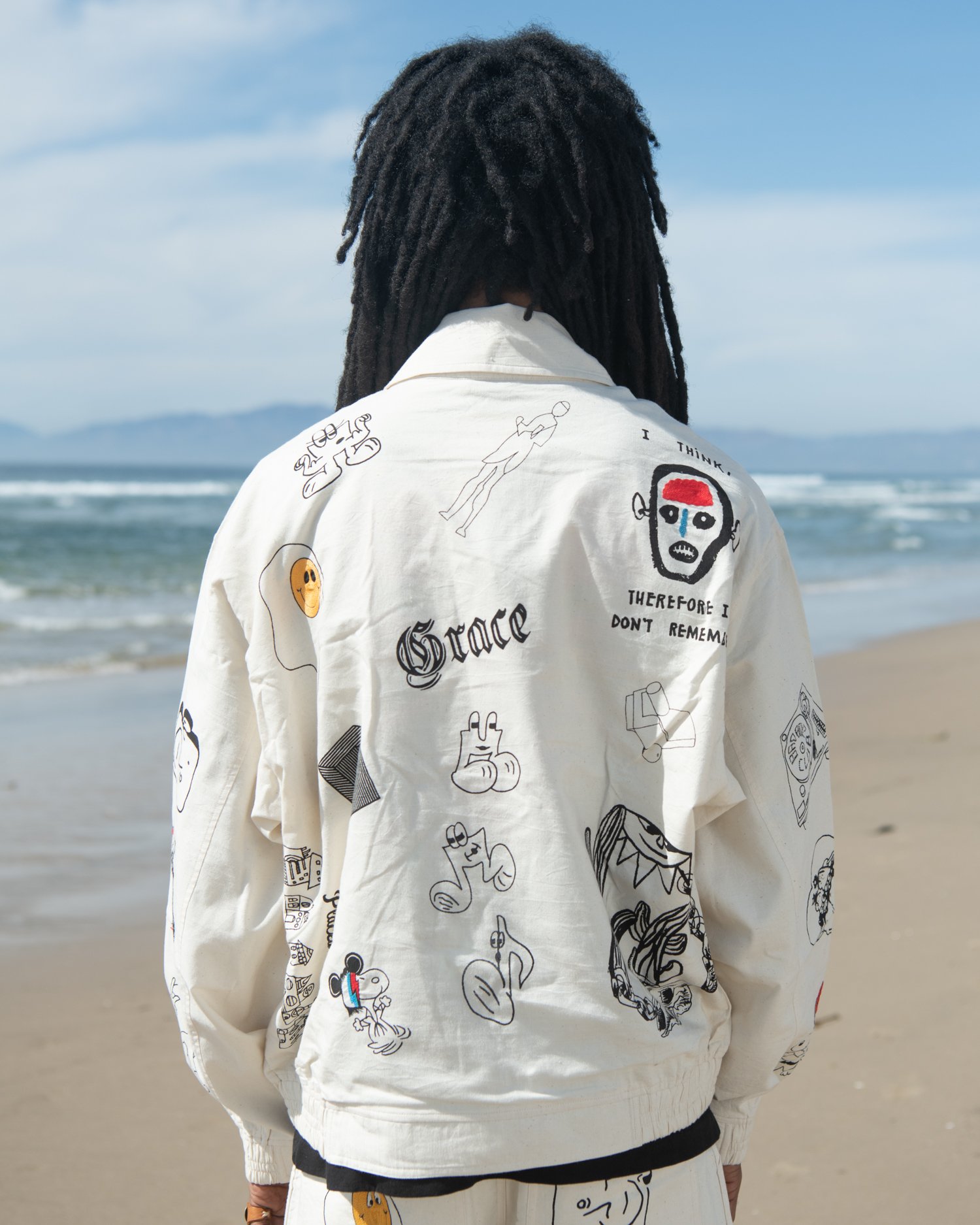 KARDO x JACOB WILDER x MONITALY collaboration hand woven Flight jacket worn by man standing on beach facing water