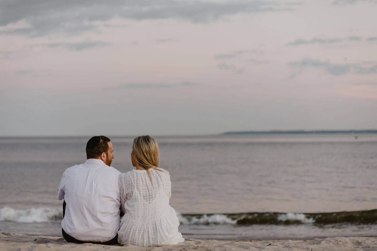 A couple sitting on the sandy beach at Fort Foster Park in Kittery, Maine