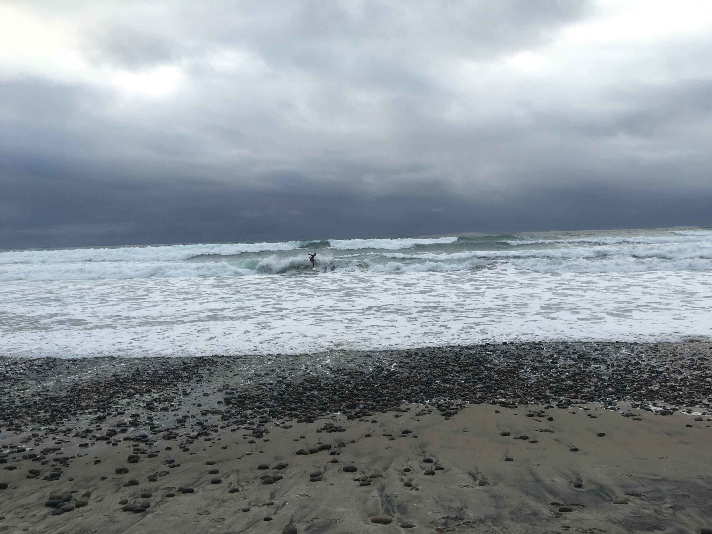 Surfer, surfing, stormy day, ocean view, Swamis beach, Encinitas, California. Image©sourcingstyle.com