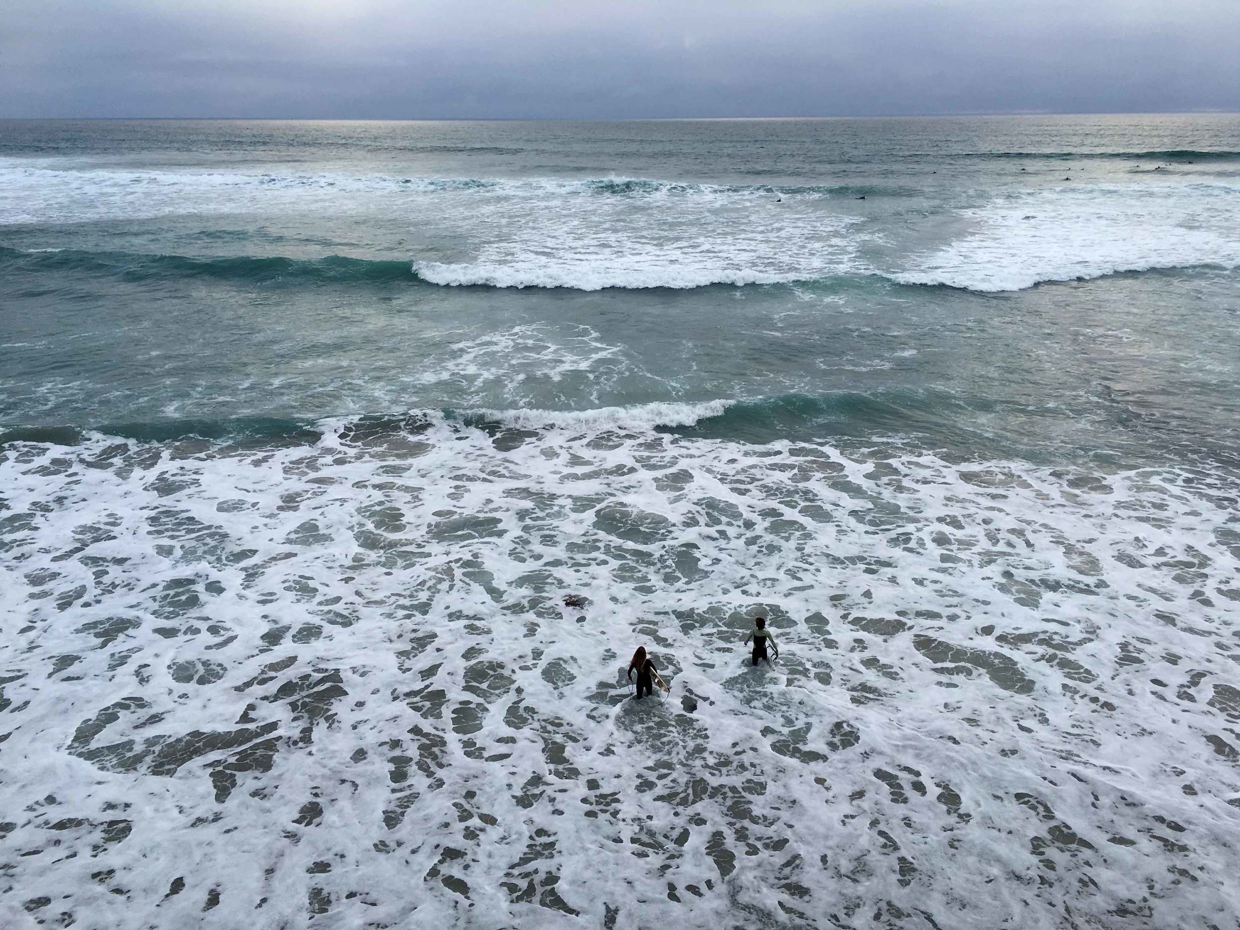 Surfers walking into the ocean, storm at the ocean, ocean view, Swamis beach, Encinitas, California. Image©sourcingstyle.com