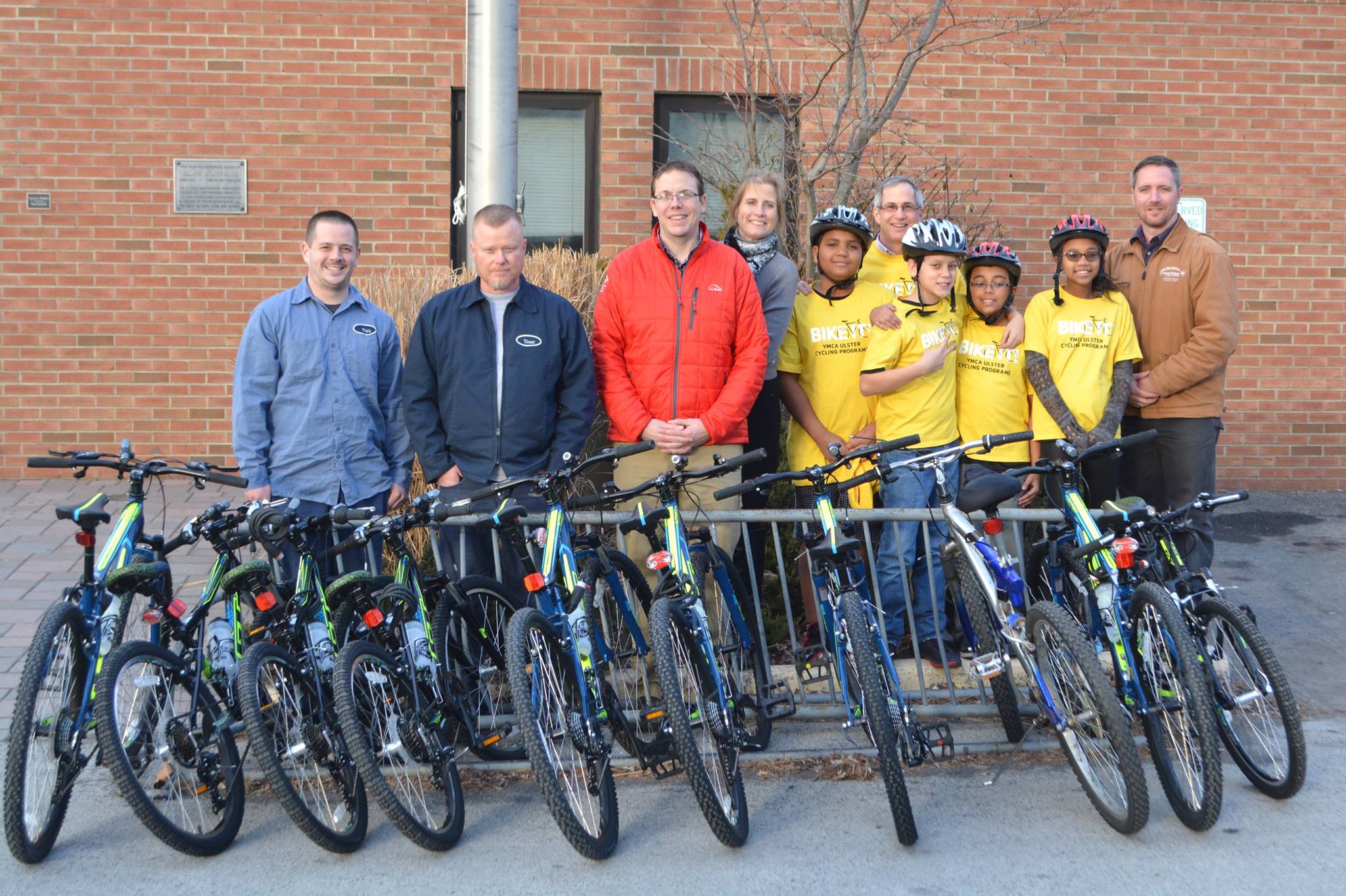 From left, Central Hudson employees Kris Mead, Vincent Boughton, and Eric Kiszkiel, YMCA President and CEO Heidi Kirschner and Bicycle Educator Tom Polk, enthusiastic youths and (far right) Central Hudson employee Michael Dooley present and accept 9bicycles for the YMCA of Kingston and Ulster County to benefit the agency’s Bike-It! program. 