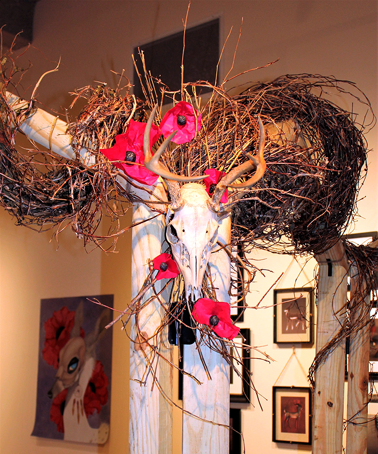  Installation detail of a real whitetail deer skull among grapevine and handmade poppies. 