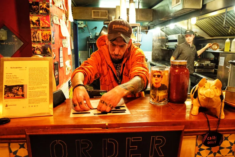 Pitmaster and owner Corey Cash puts tape over sold-out items during the last night Williamsburg's Cash Only BBQ was open.