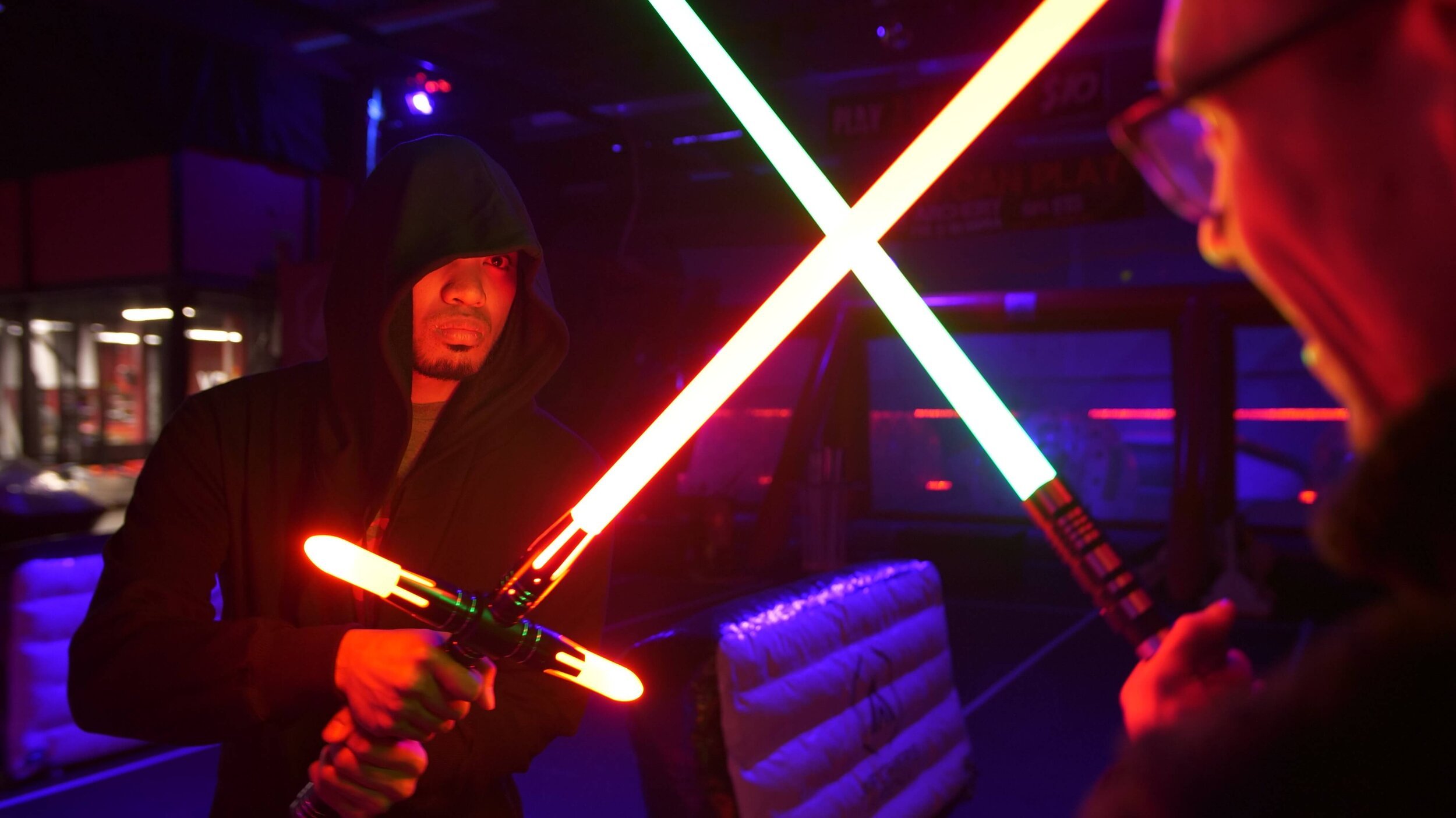 Two players dueling with glowing lightsabers at Toronto's only Saber Wars arena