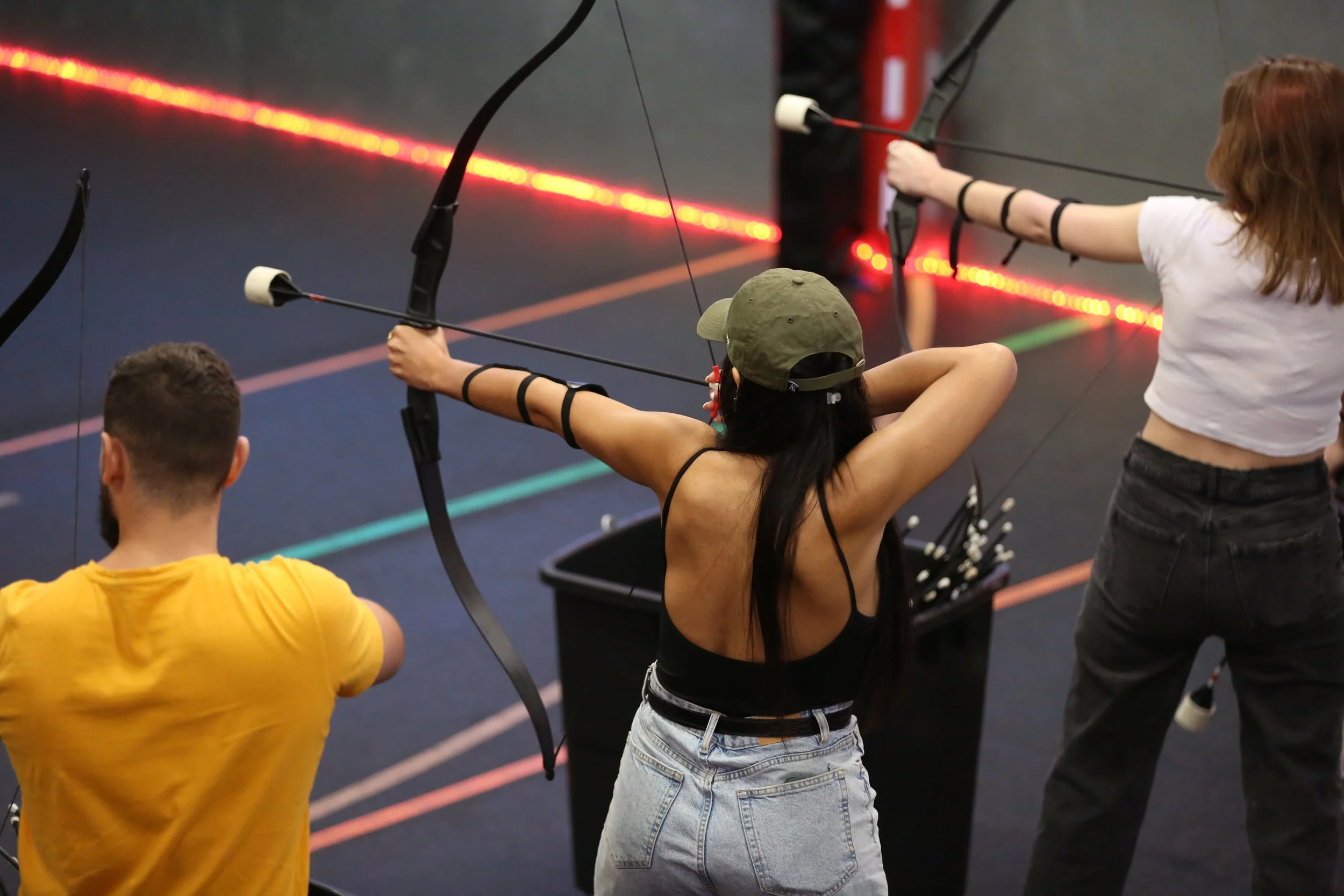 first time archery players aiming at targets indoor training session