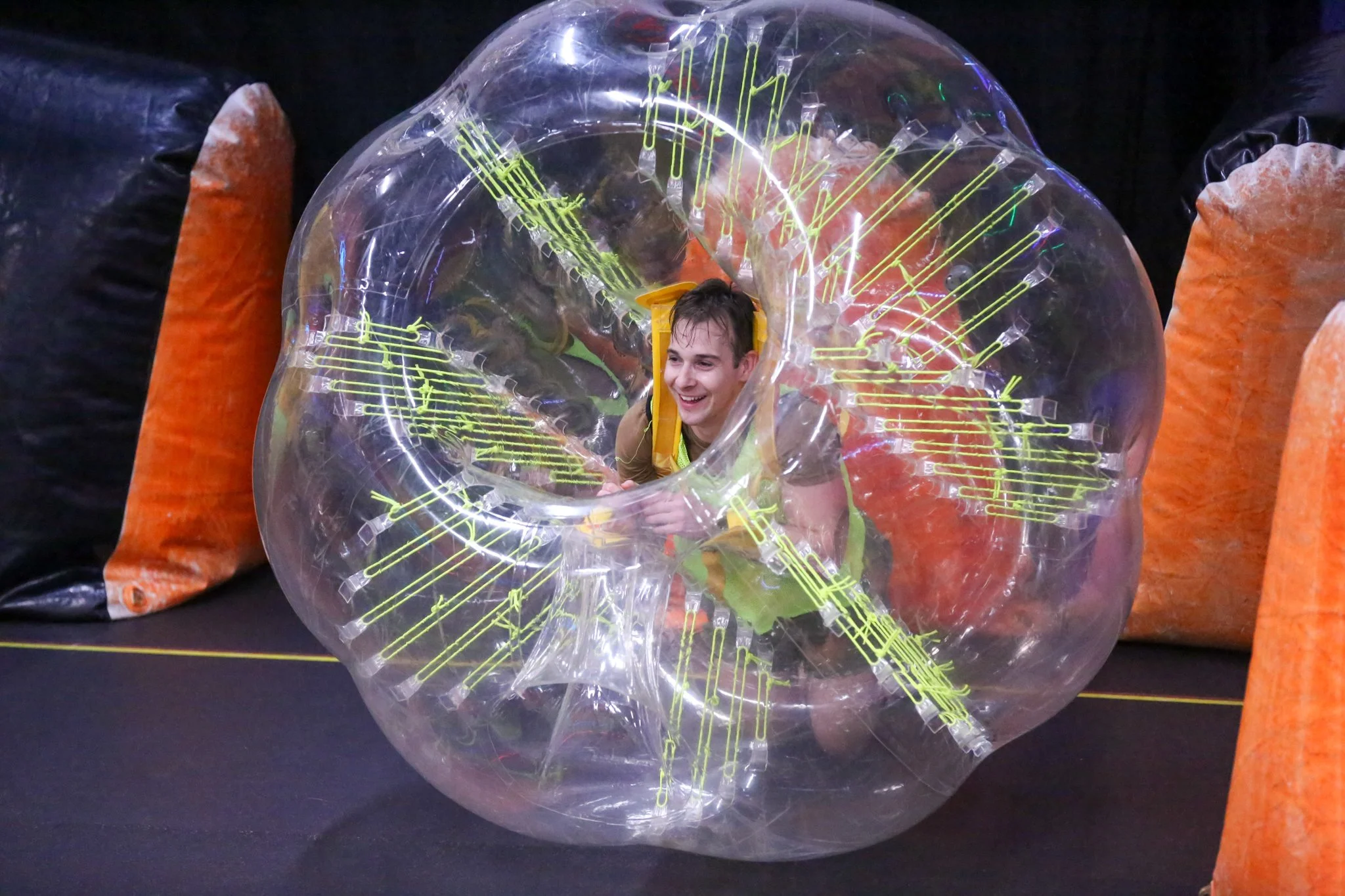 Adults laughing while playing bubble soccer and colliding in inflatable suits