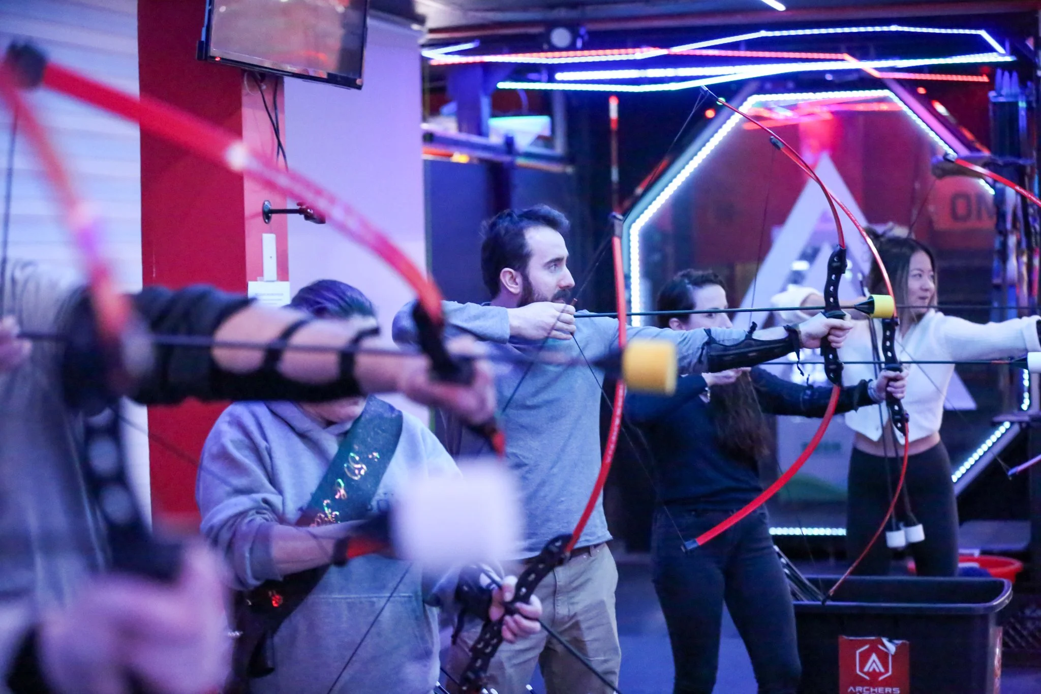 Adults participating in beginner archery lessons in Toronto indoor arena