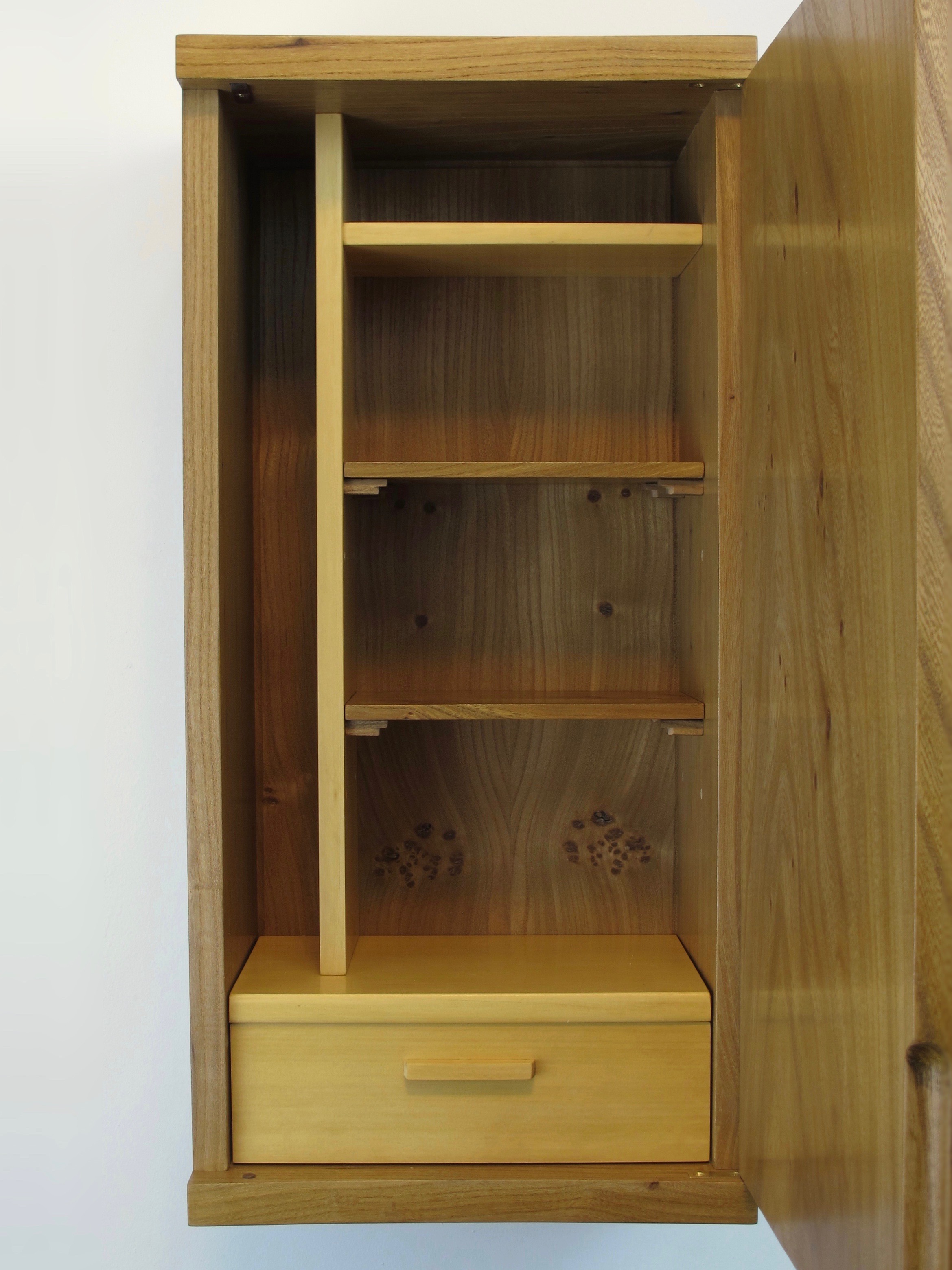 The interior has two moveable shelves, a single drawer at the bottom and two cubbies, at the top right and left hand side.