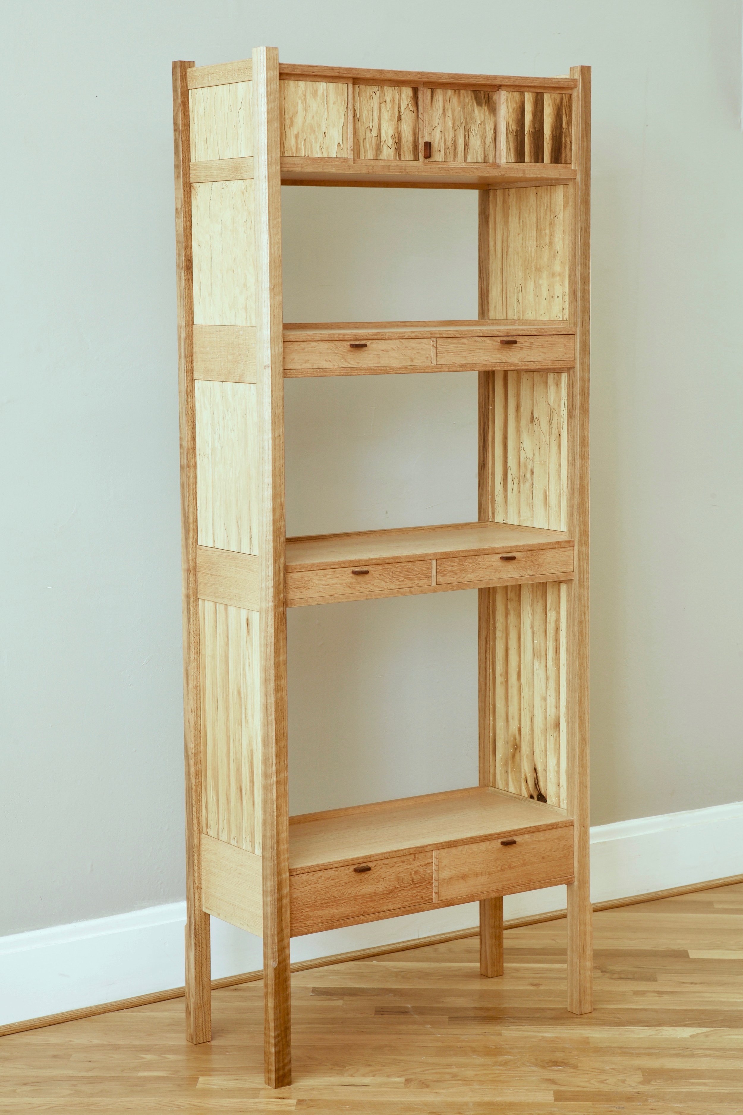 The piece is “post and panel” construction, a process in which the sides are constructed first with floating panels and long, full height legs, after which the shelves, back rails and interior components are made and assembled.