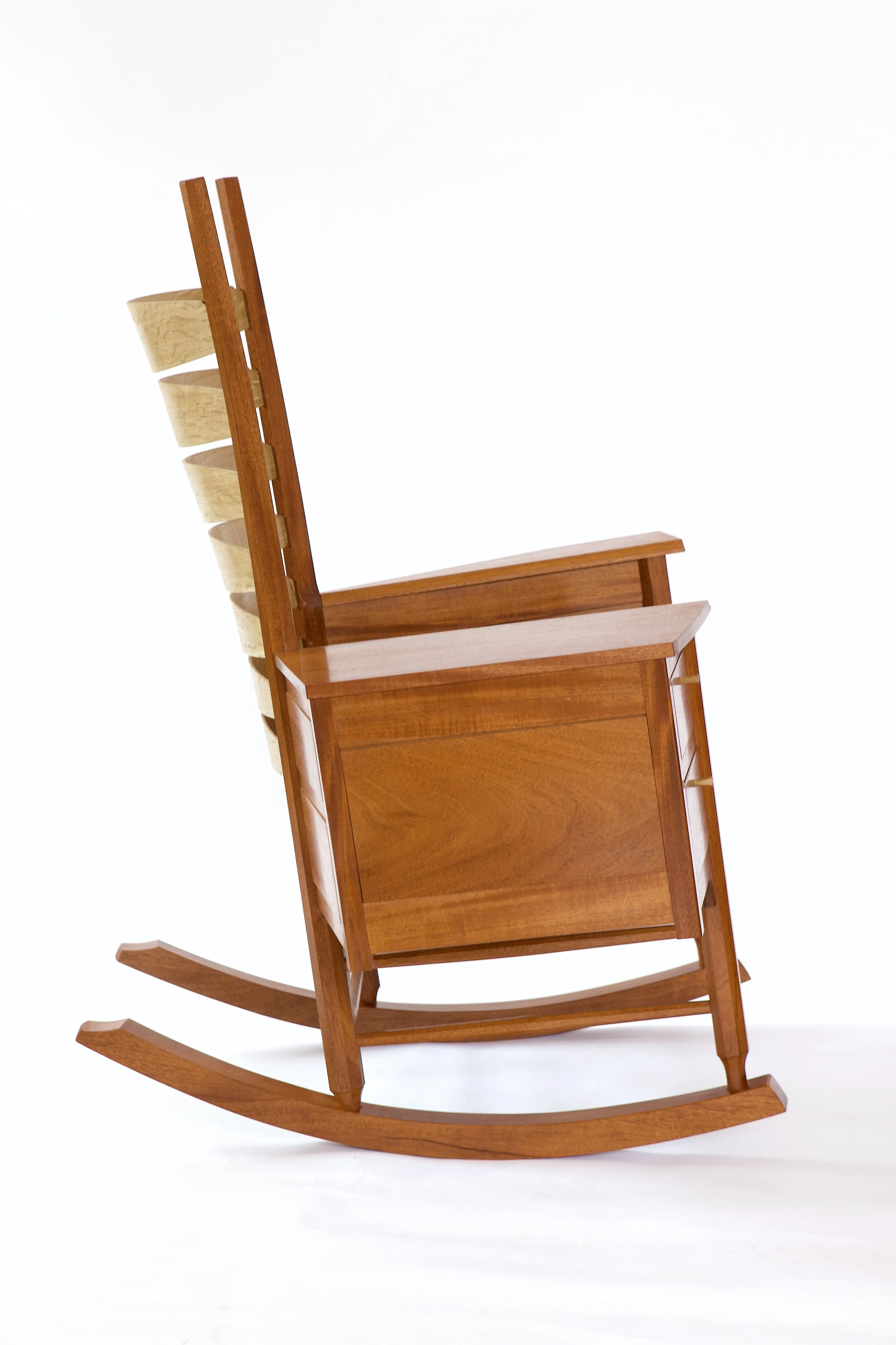  Other than the obvious inclusion of a pair of drawers beneath one arm, this chair is a relatively straightforward post-and-rung ladderback rocking chair. The slat and seat geometry give good lower back support and a nice lean. 