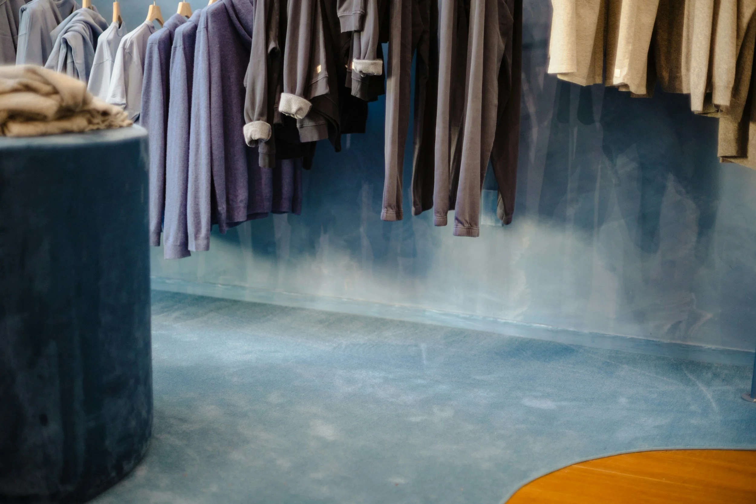 Clothing racks with various sweaters and hoodies hanging in a store.
