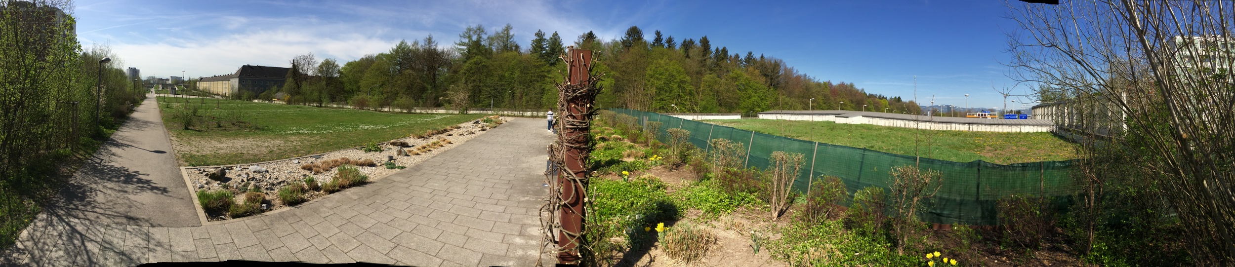 Panoramic view of the park on top of the Bindermichl tunnel. To the right, blue road signs can be seen at the tunnel exit. 