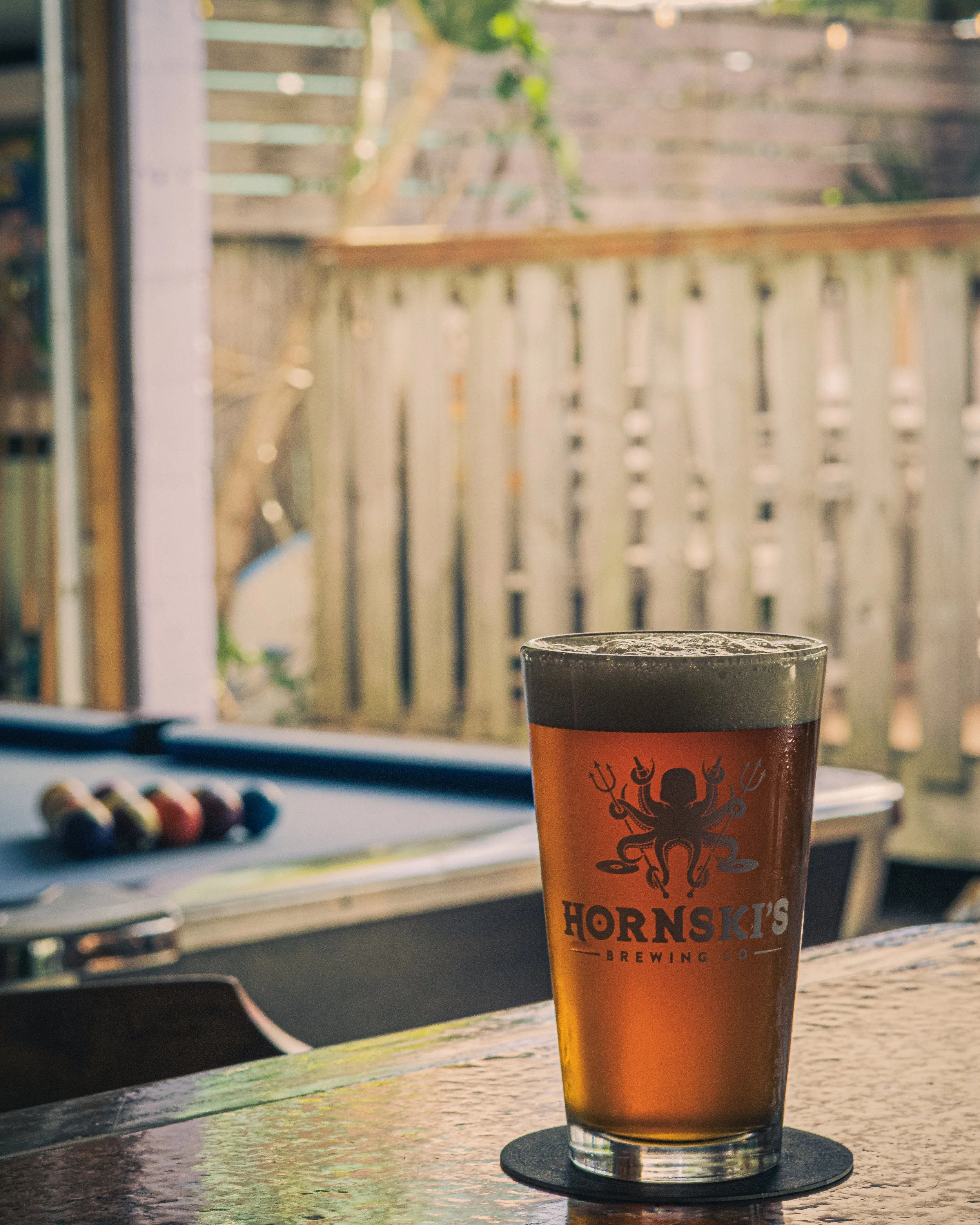 Amber Beer in front of a pool table and an outdoor seating area
