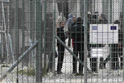 Immigrants stand behind a fence at a detention centre in the Amygdaleza suburb of western Athens February 14, 2015. REUTERS/ Alkis Konstantinidis