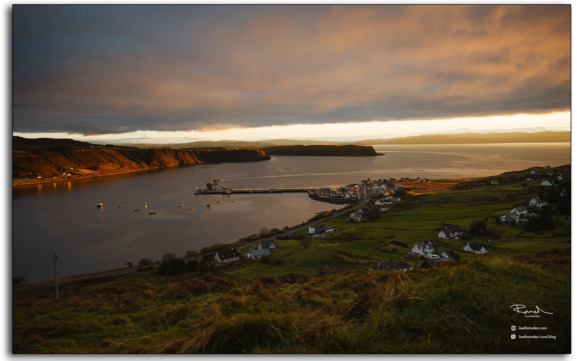 Golden sunset over Uig Harbour on the Isle of Skye, Scotland, with warm light reflecting across the bay and cottages nestled on the hillside