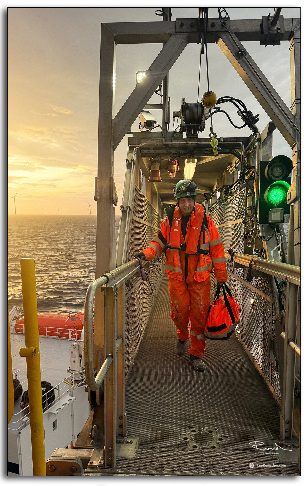 Wind farm technician crossing walk to work gangway during crew transfer