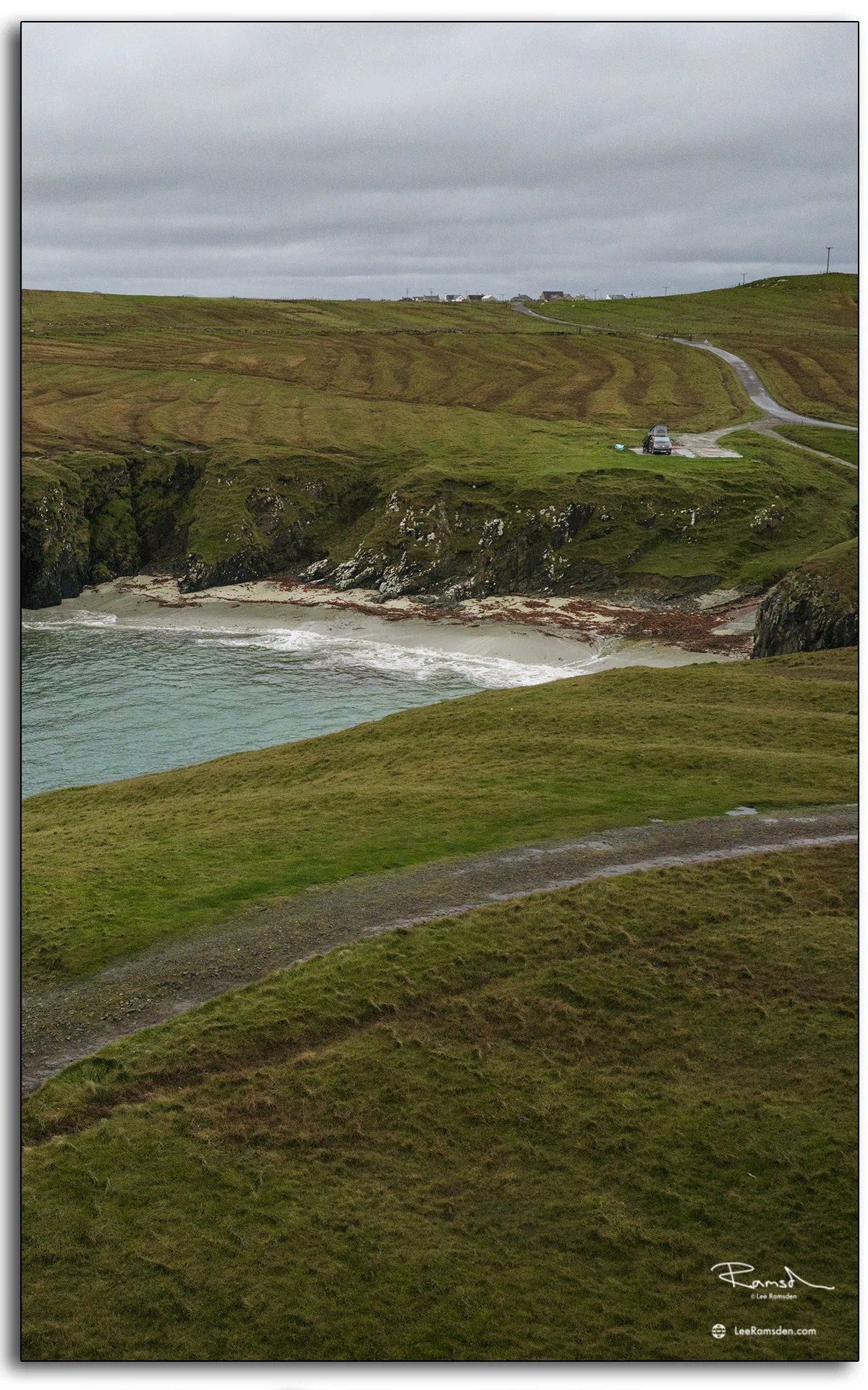 Aerial view of a secluded beach and winding road near the Butt of Lewis, Isle of Lewis, Scotland, showing rugged cliffs and Atlantic waves