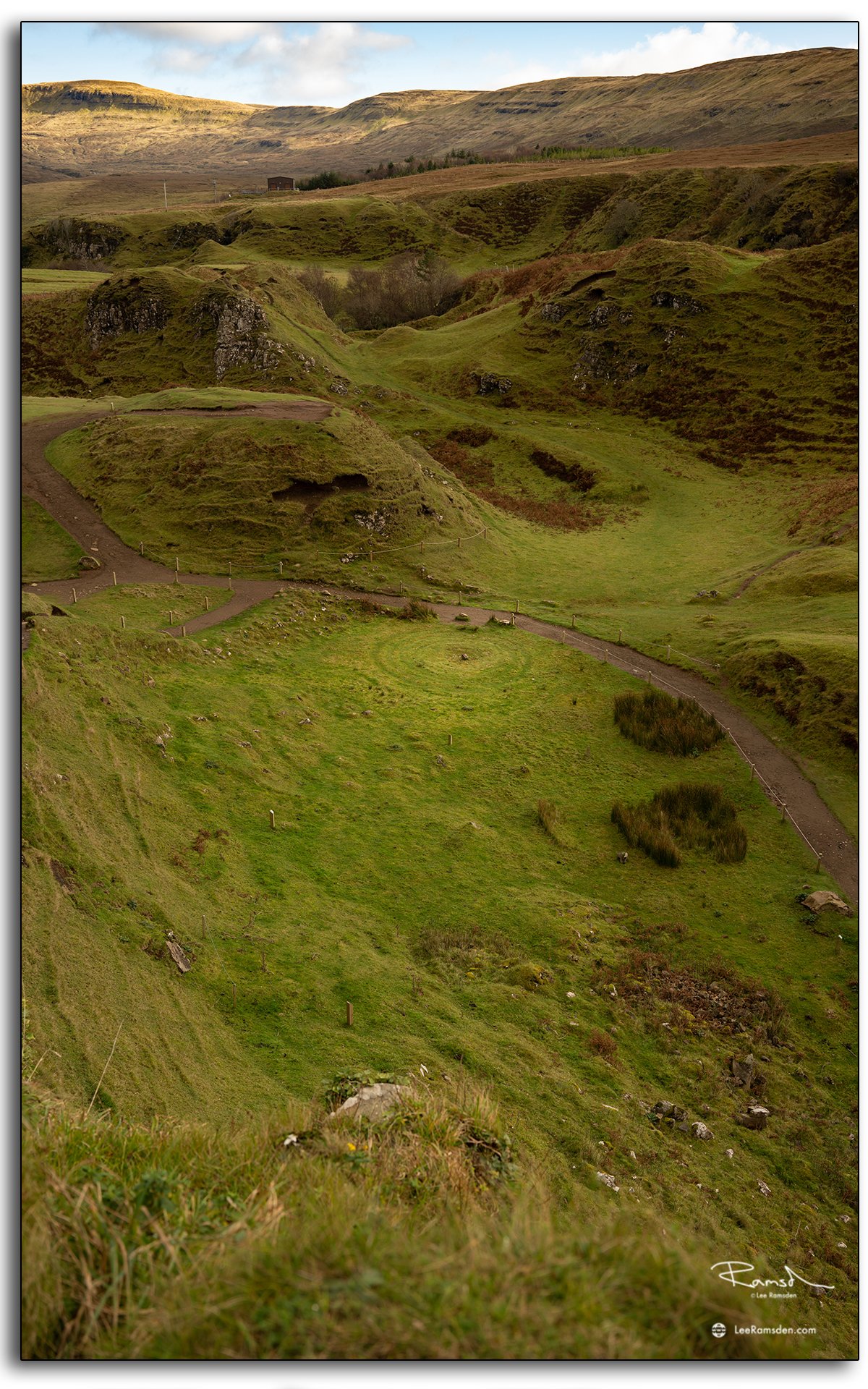 iew over the Fairy Glen on the Isle of Skye, featuring a stone spiral and a lone cottage nestled among rolling green hills